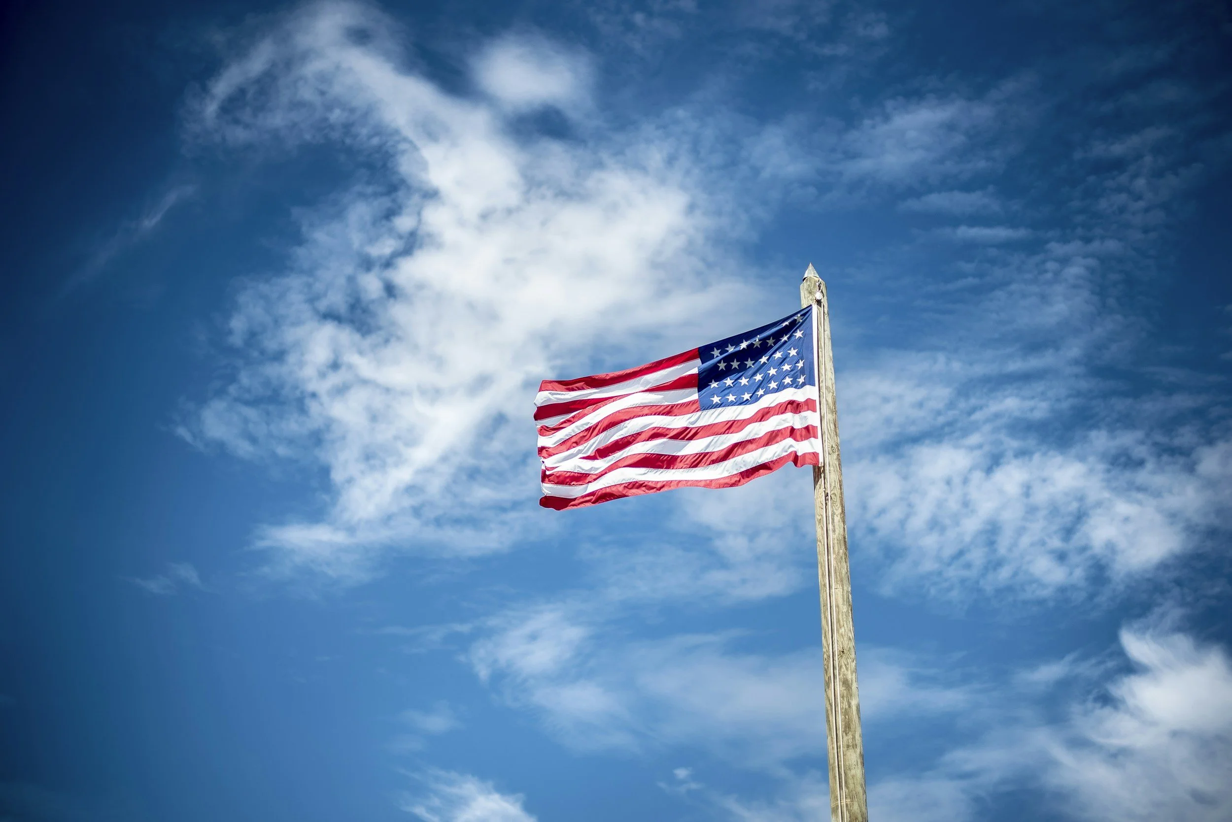 American flag waving in the sky representing belonging, bicultural identity, and the Korean American experience.