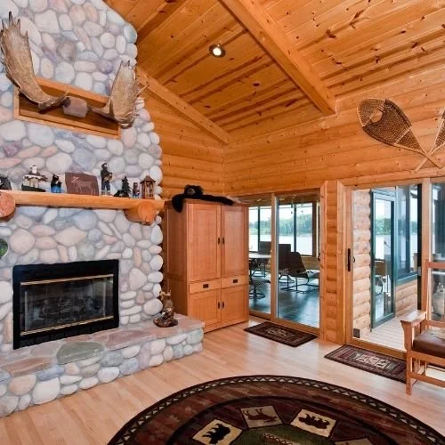 Interior view of a high-end custom log home with a river rock fireplace.