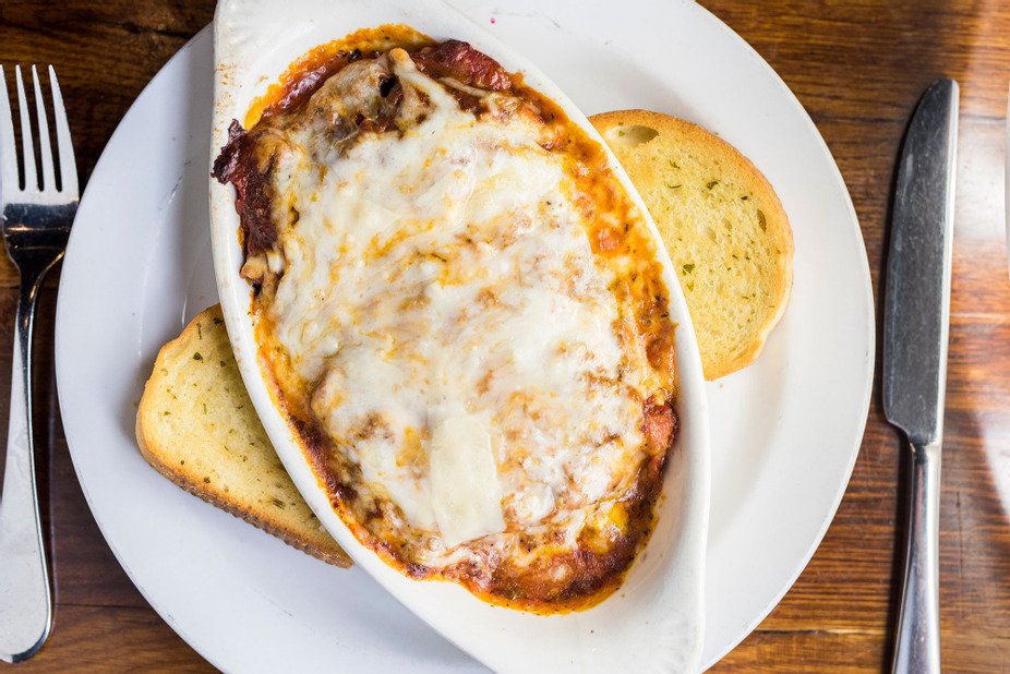 Lasagna topped with melted cheese, served with crispy garlic bread.