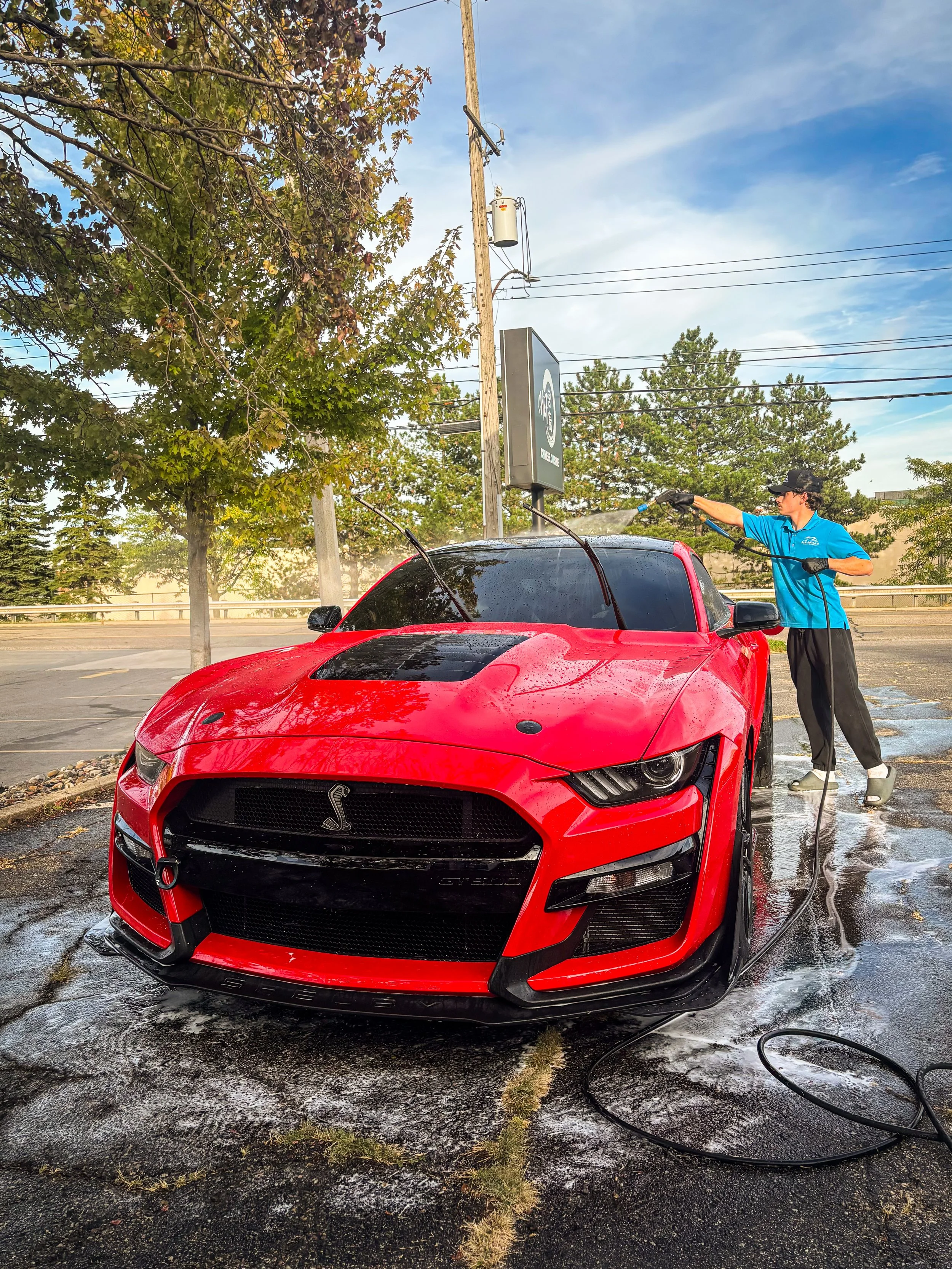 A bright red Shelby Mustang GT500 with a mirror-like finish after a professional exterior detail in Lansing, Michigan.