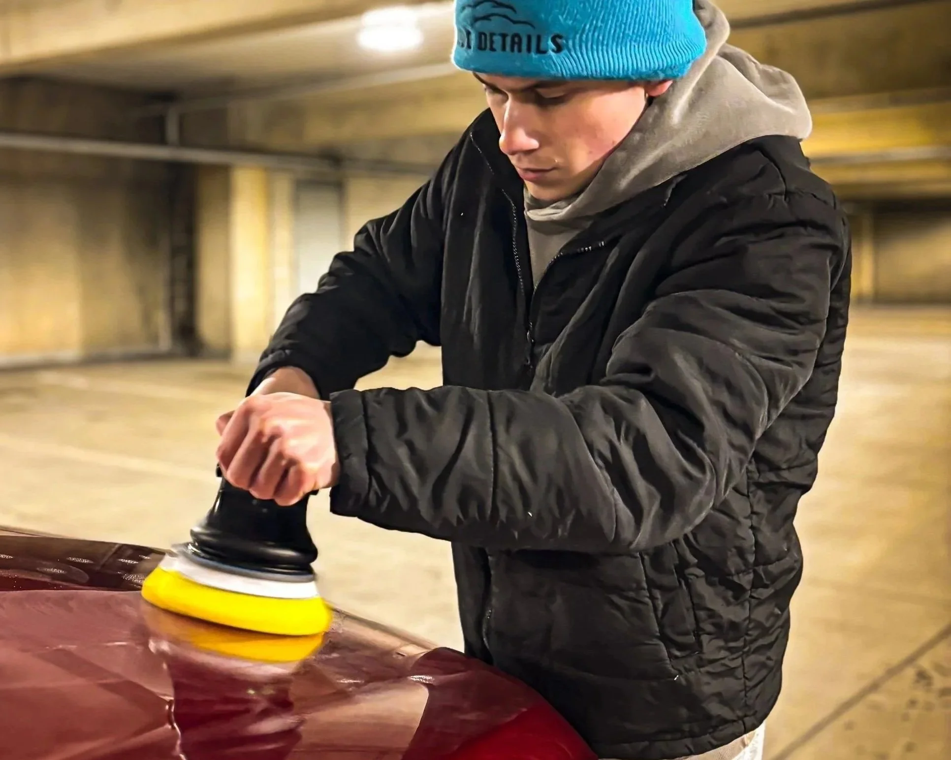 Removing heavy swirl marks and scratches from a vehicle's clear coat in Lansing, MI, using a professional dual-action polisher and cutting compound.