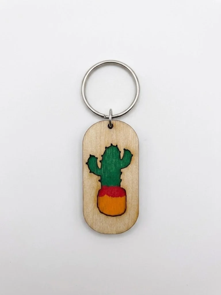 Wooden keychain with a green cactus inside a small, painted pot, attached to a metal keyring.