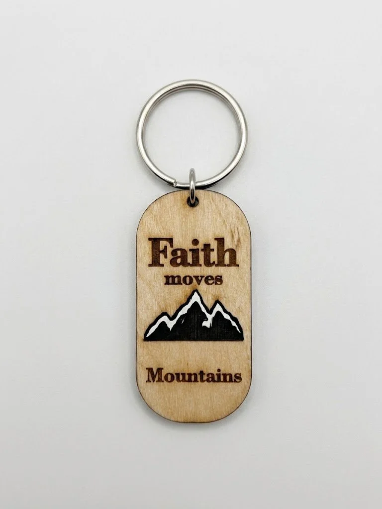 Wooden keychain with a mountain design and the inscription 'Faith moves Mountains'.