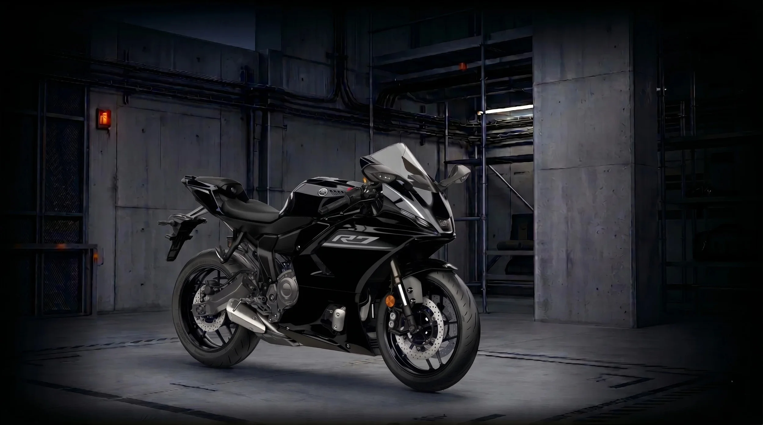 Moto noire Yamaha R7 dans un parking industriel sombre