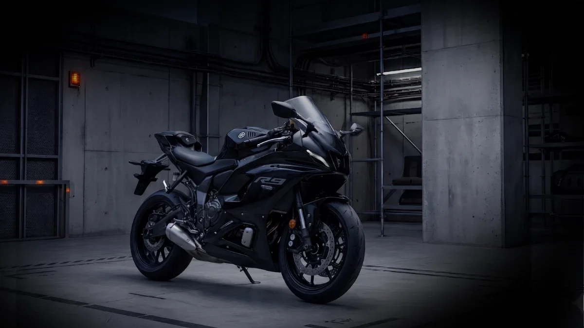 Une moto noire de sport Yamaha R6 dans un parking souterrain sombre en béton.