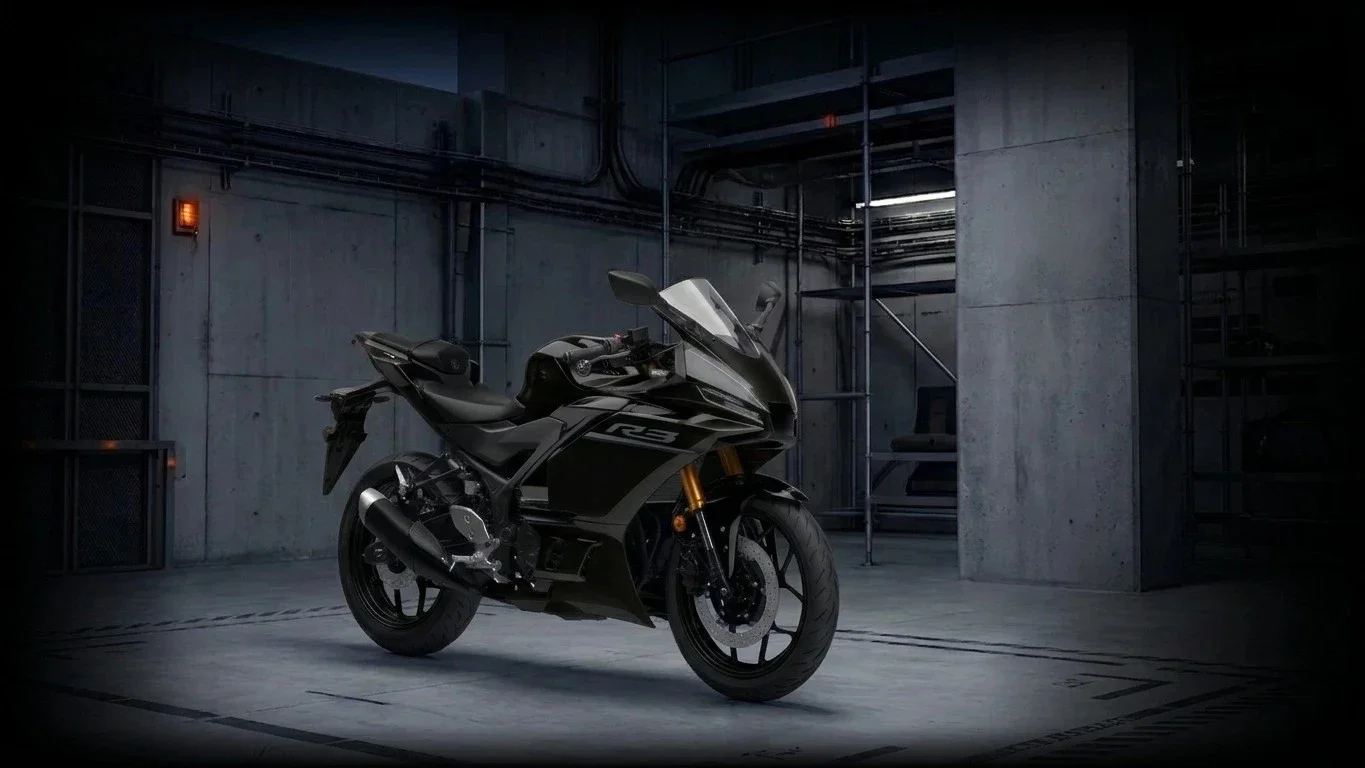 Une moto noire dans un garage en béton, éclairée par une lumière artificielle.