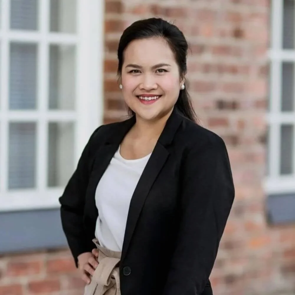 Renting Out Your House - The Essential Host (Smiling young professional woman rental property owner standing in front of brick home)