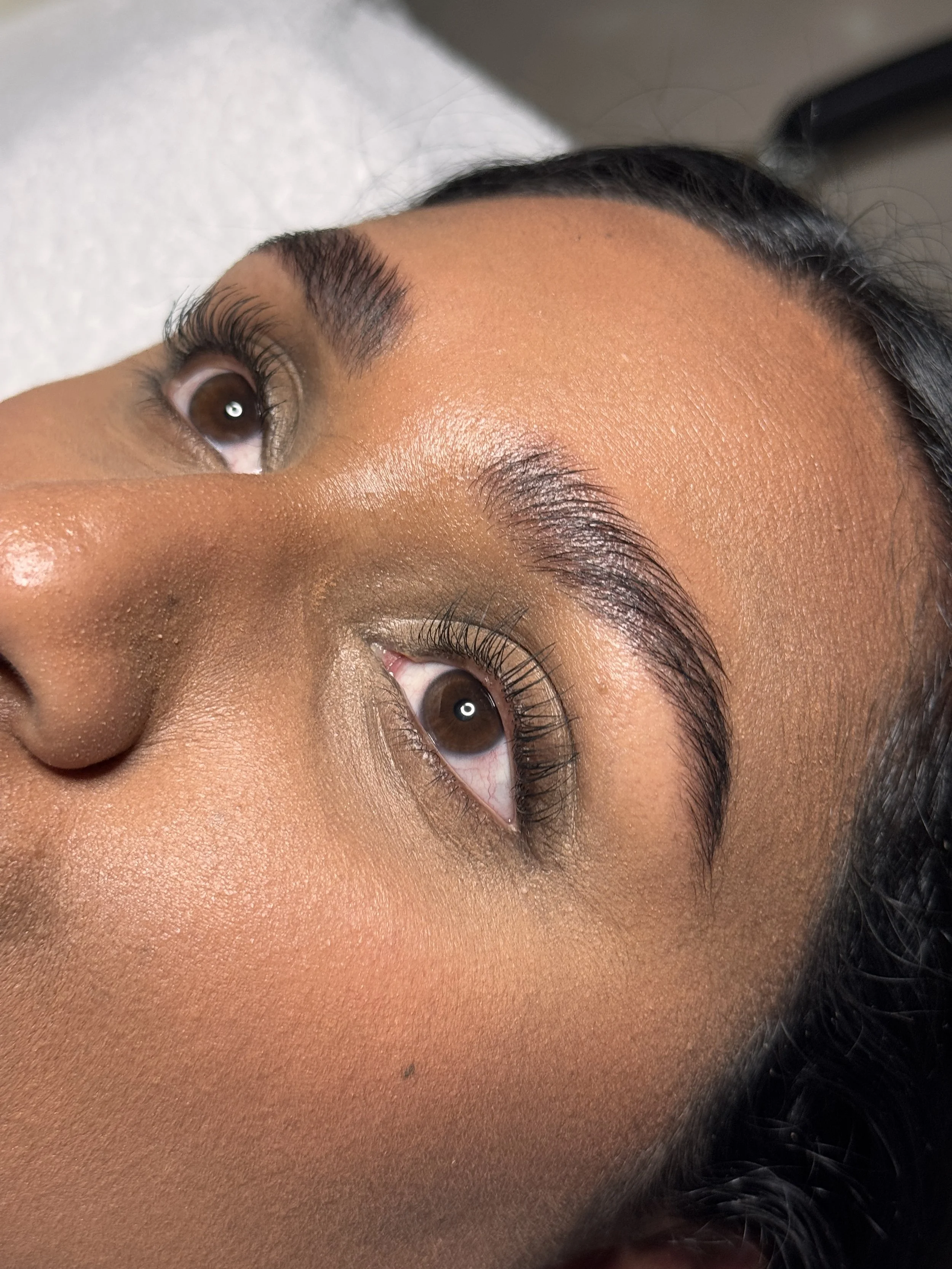 Close-up of a person's face focusing on the eyes, eyelashes, and eyebrows with a background of a white towel.