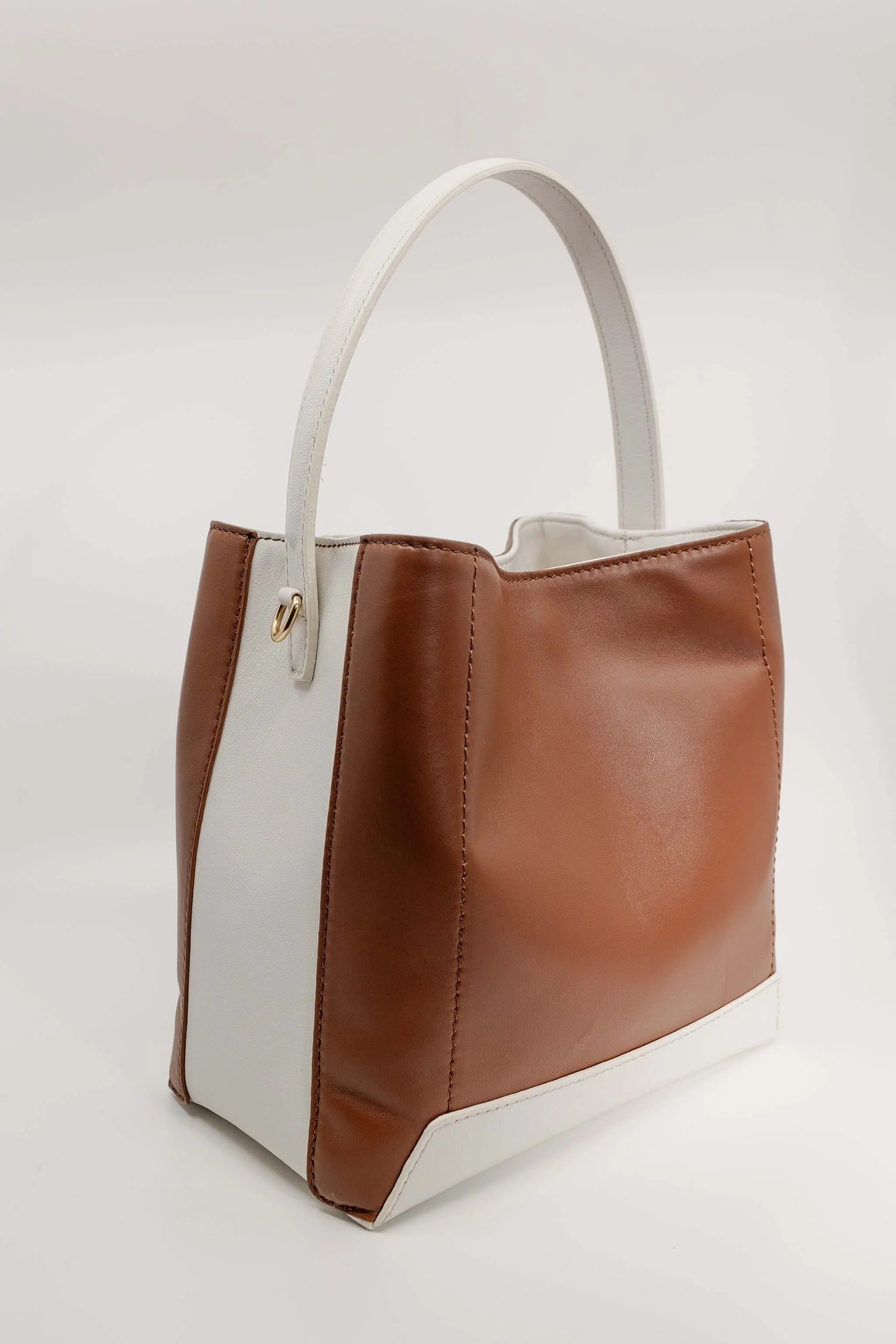 A stylish tote bag with vertical color blocks in white, brown, and tan leather, featuring a white handle and white base.