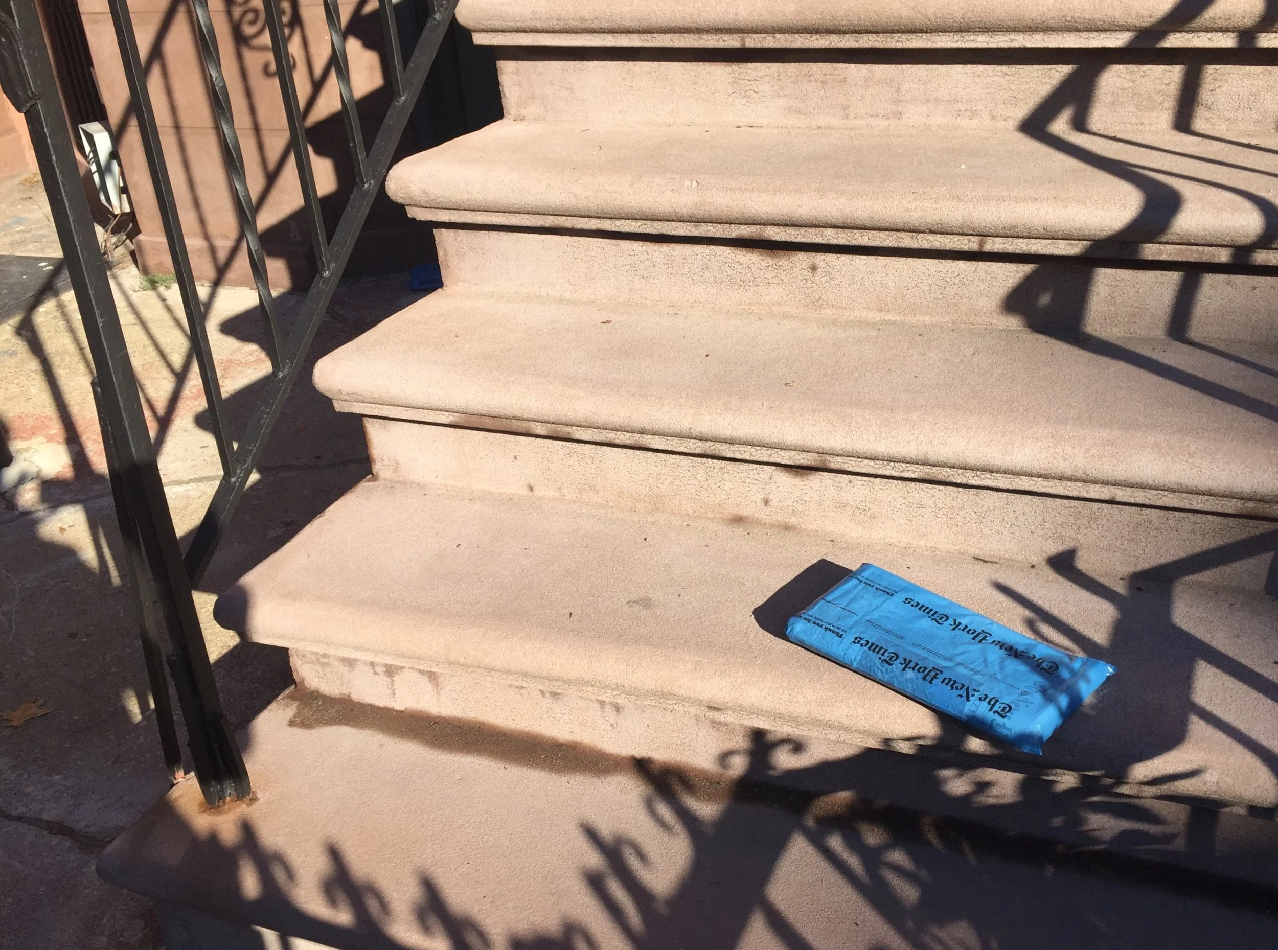 Betonstufen vor einer schwarzen Metalltreppe, auf einer Stufe liegt eine blaue Plastiktüte.