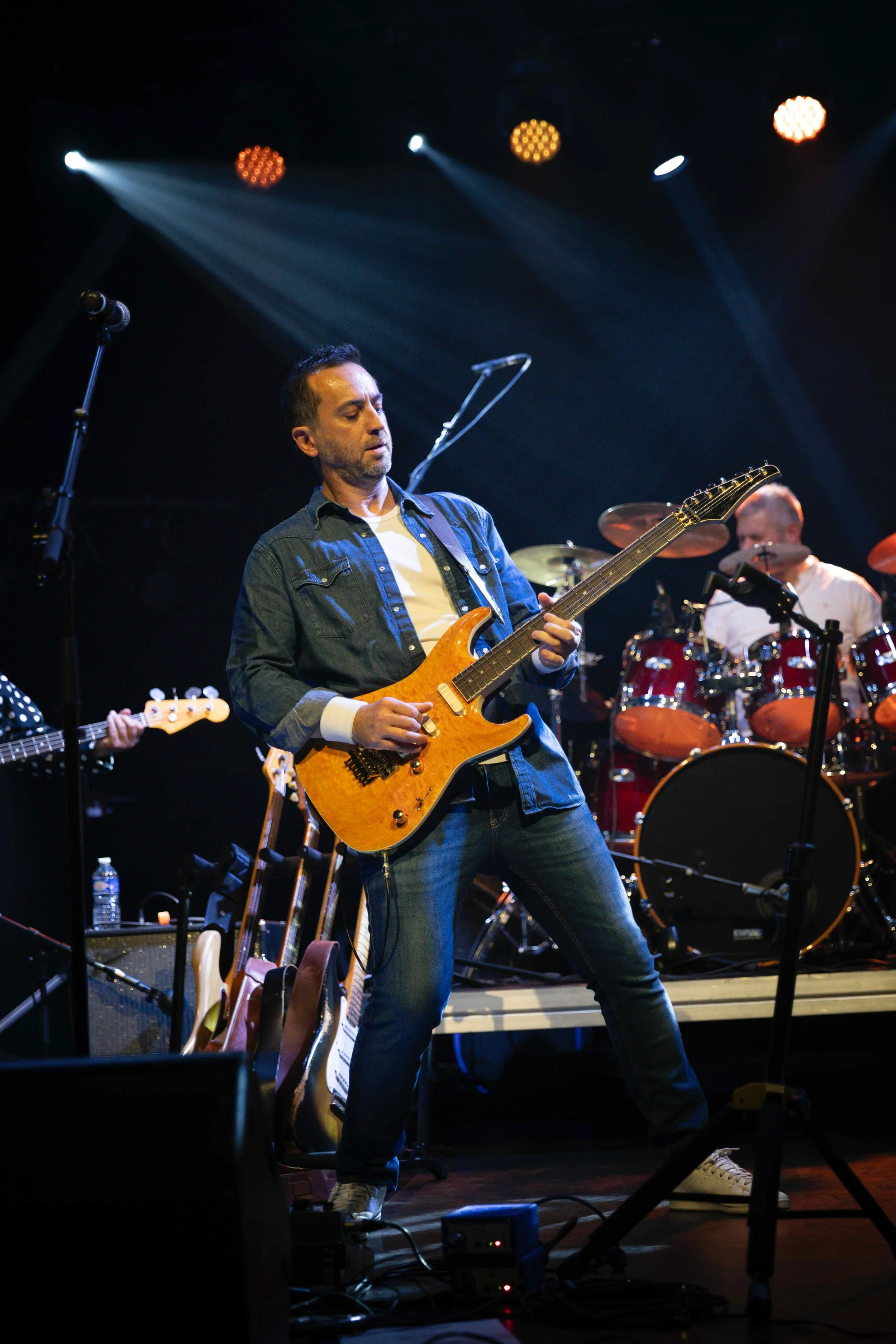 Musicien jouant de la guitare électrique lors d'un concert avec des éclairages de scène.