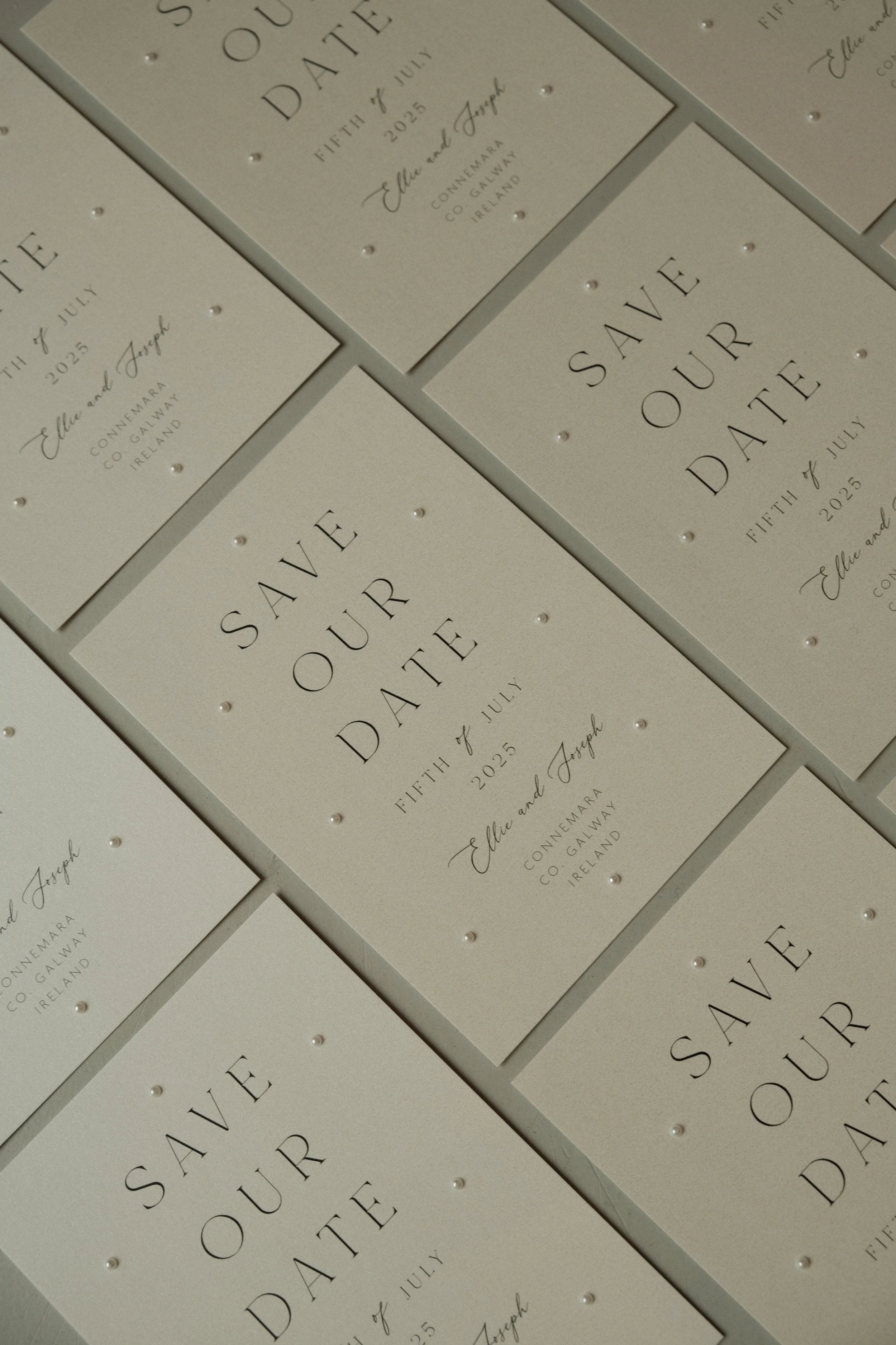 Multiple wedding save the date cards with elegant text and small pearl embellishments.