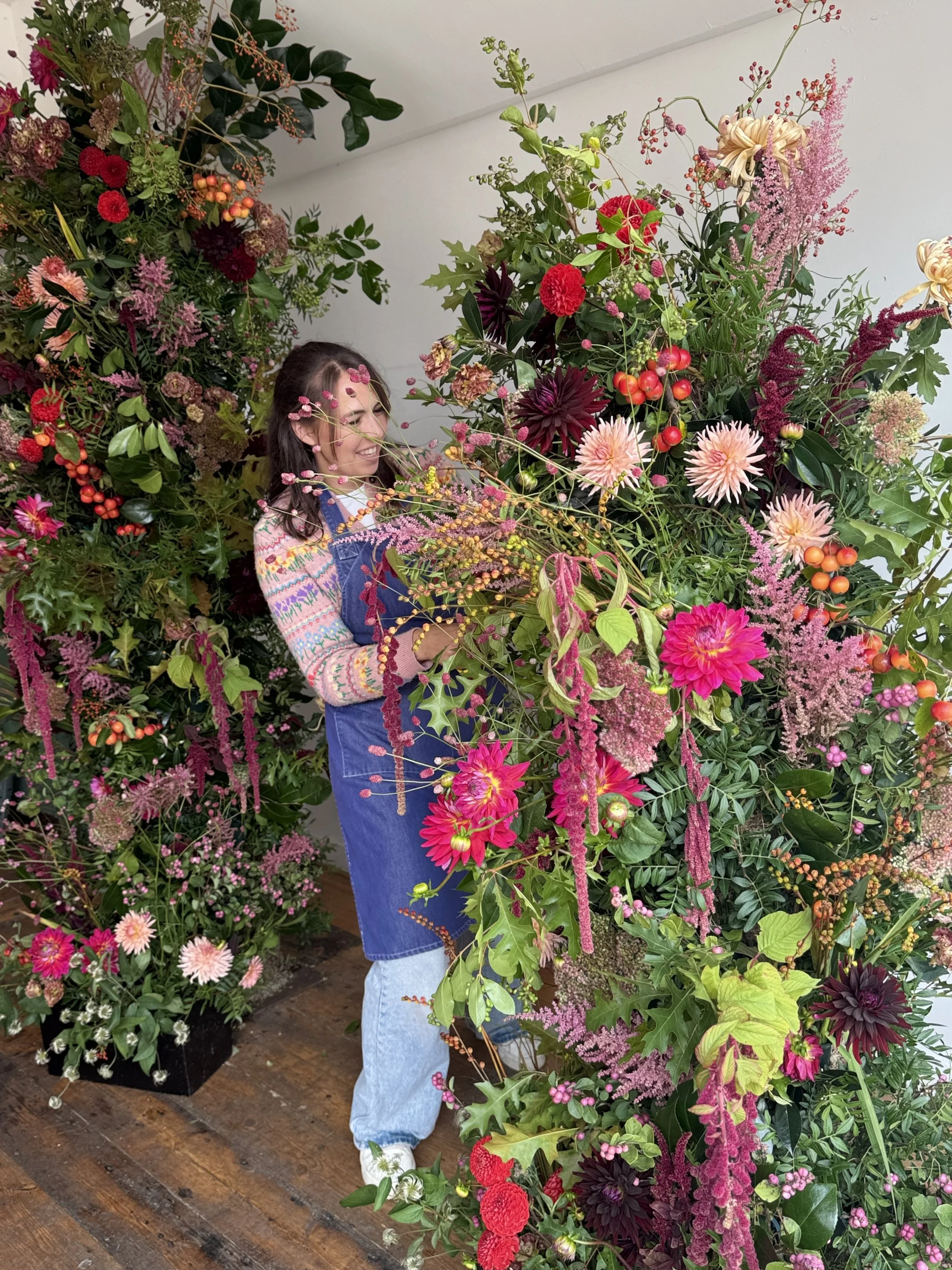 A flower farmer florist creating a large colourful floral arch for a wedding or event