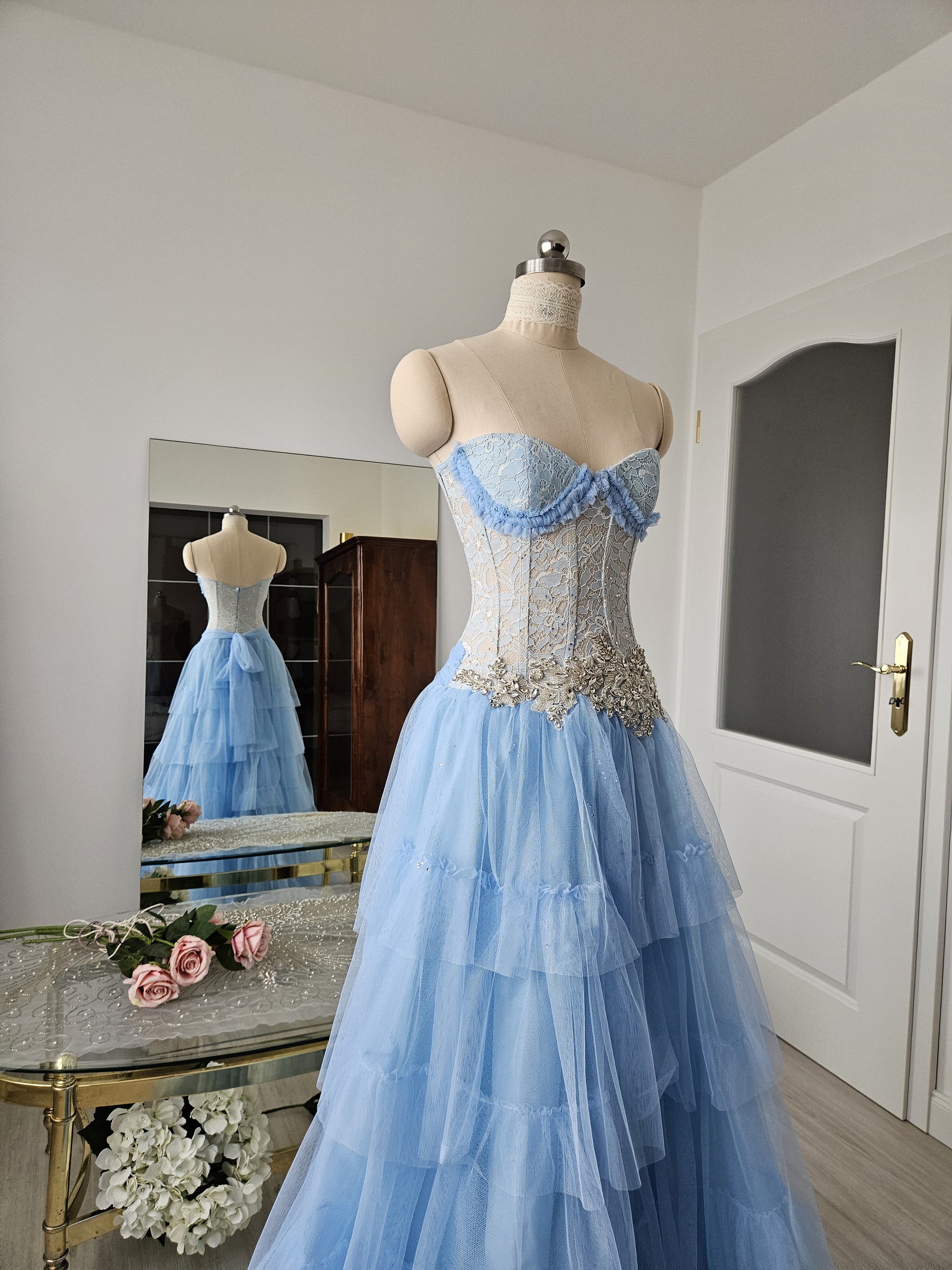 Korsettkleid aus Tüll und Spitze in hellblau / periwinkle, mit hochwertiger, glitzernder Brautkleidapplikation, mit ausladendem, abgestuftem Tüllrock in Bodenlänge. Couture-Kleid als Gala-Kleid