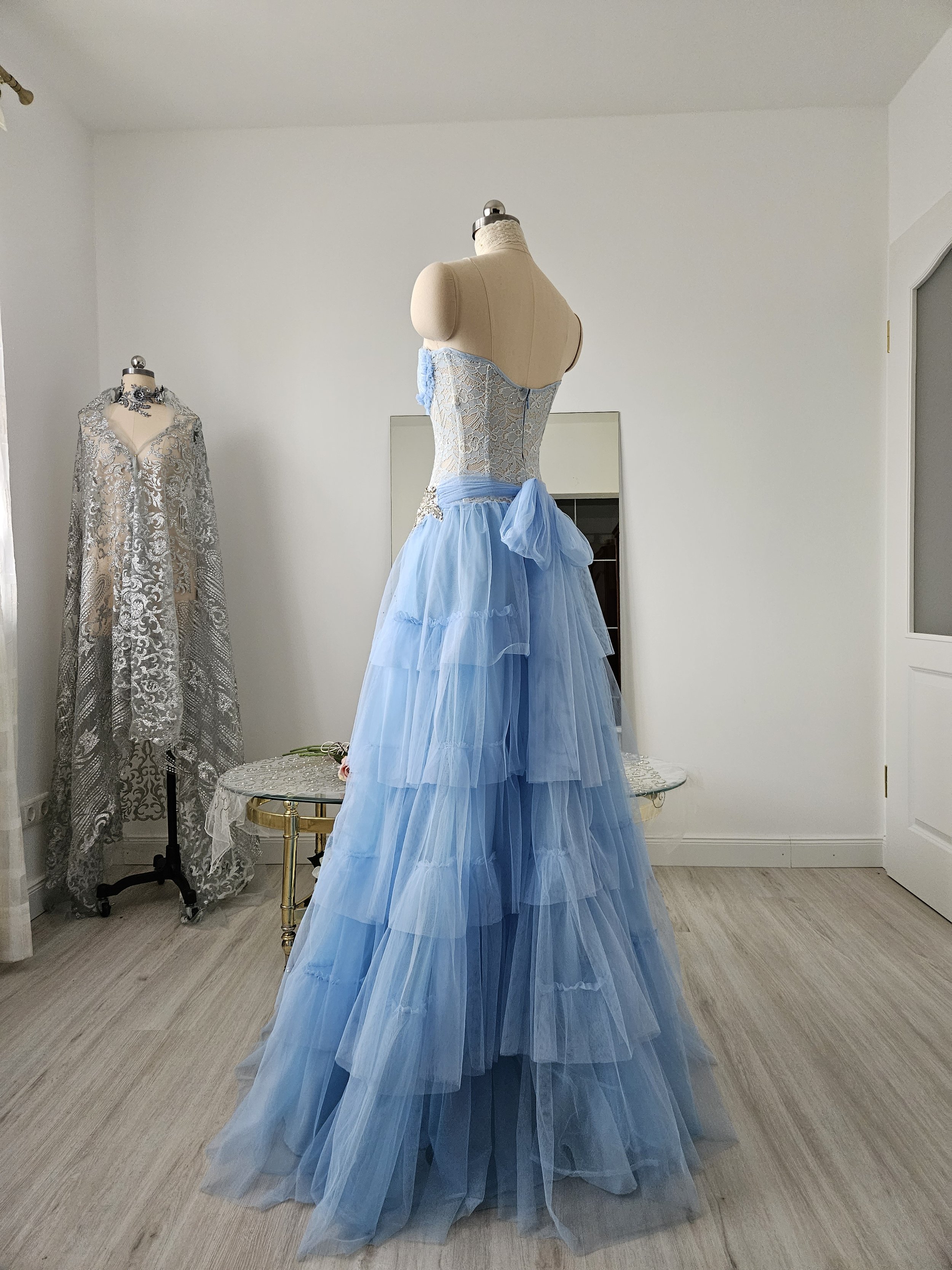 schräge Rückansicht Korsettkleid in periwinkle Spitze, mit Tüll-Rock und großer Zierschleife hinten. Couture aus Deutschland