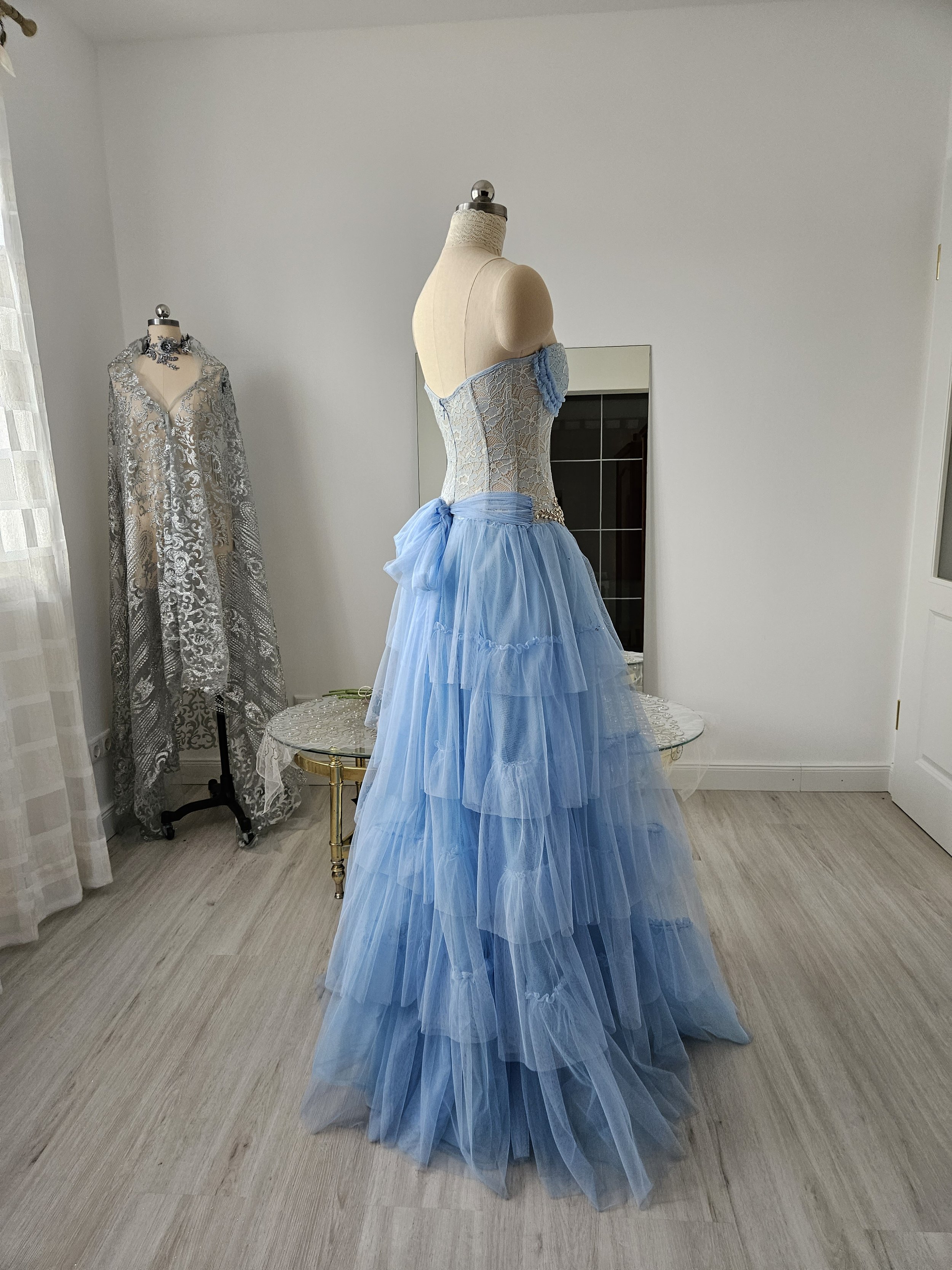 Korsettkleid in hellblau, mit bodenlangem, abgestuftem Rock aus leichtem Tüll und großer Schleife hinten, gefertigt aus feiner Spitze. Couture aus Deutschland