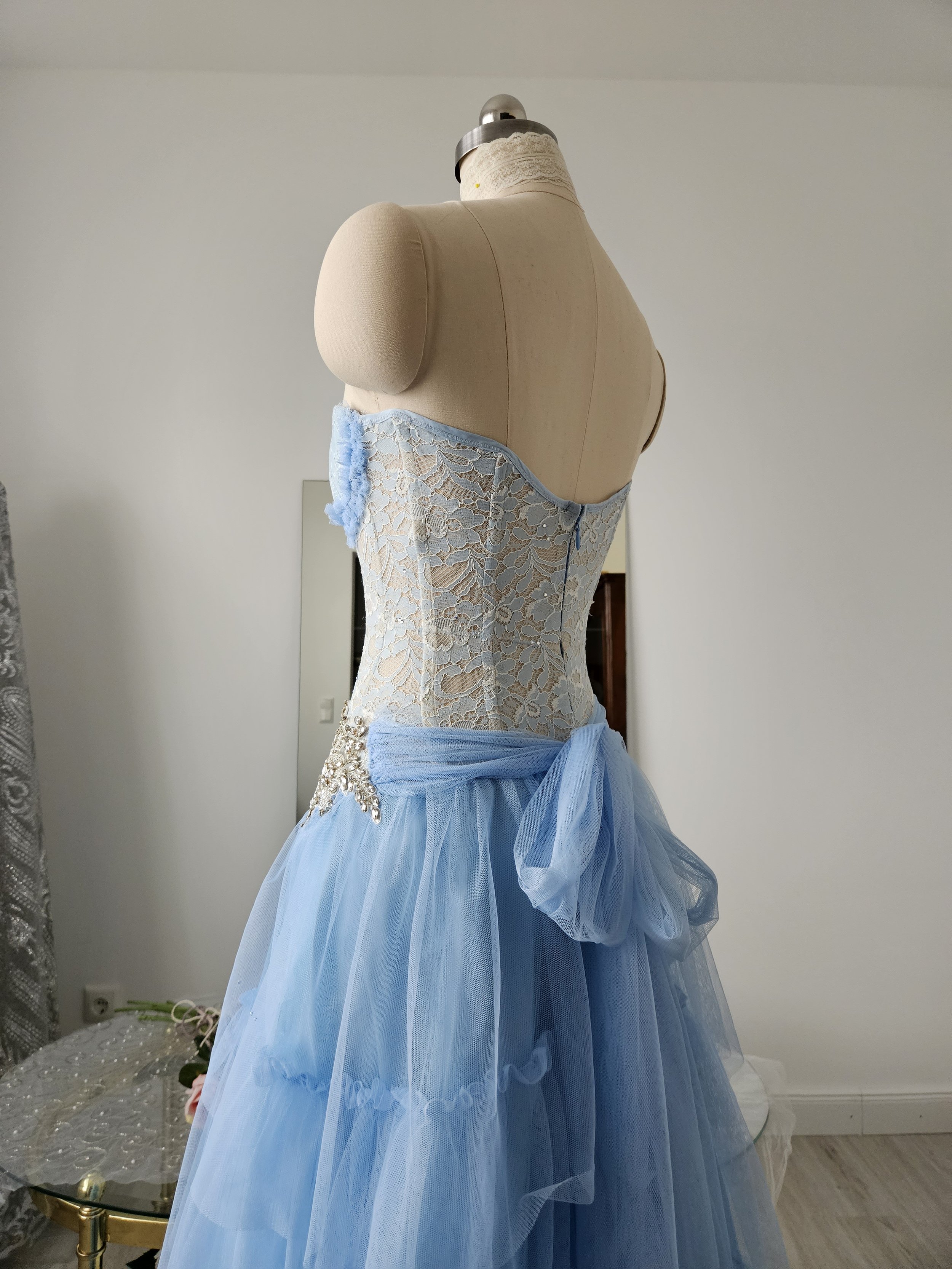 Nahaufnahme Rückansicht trägerloses Korsettoptik-Kleid aus Blumenspitze in pastellblau mit Tüllrock und großer Tüllschleife, Handarbeit.