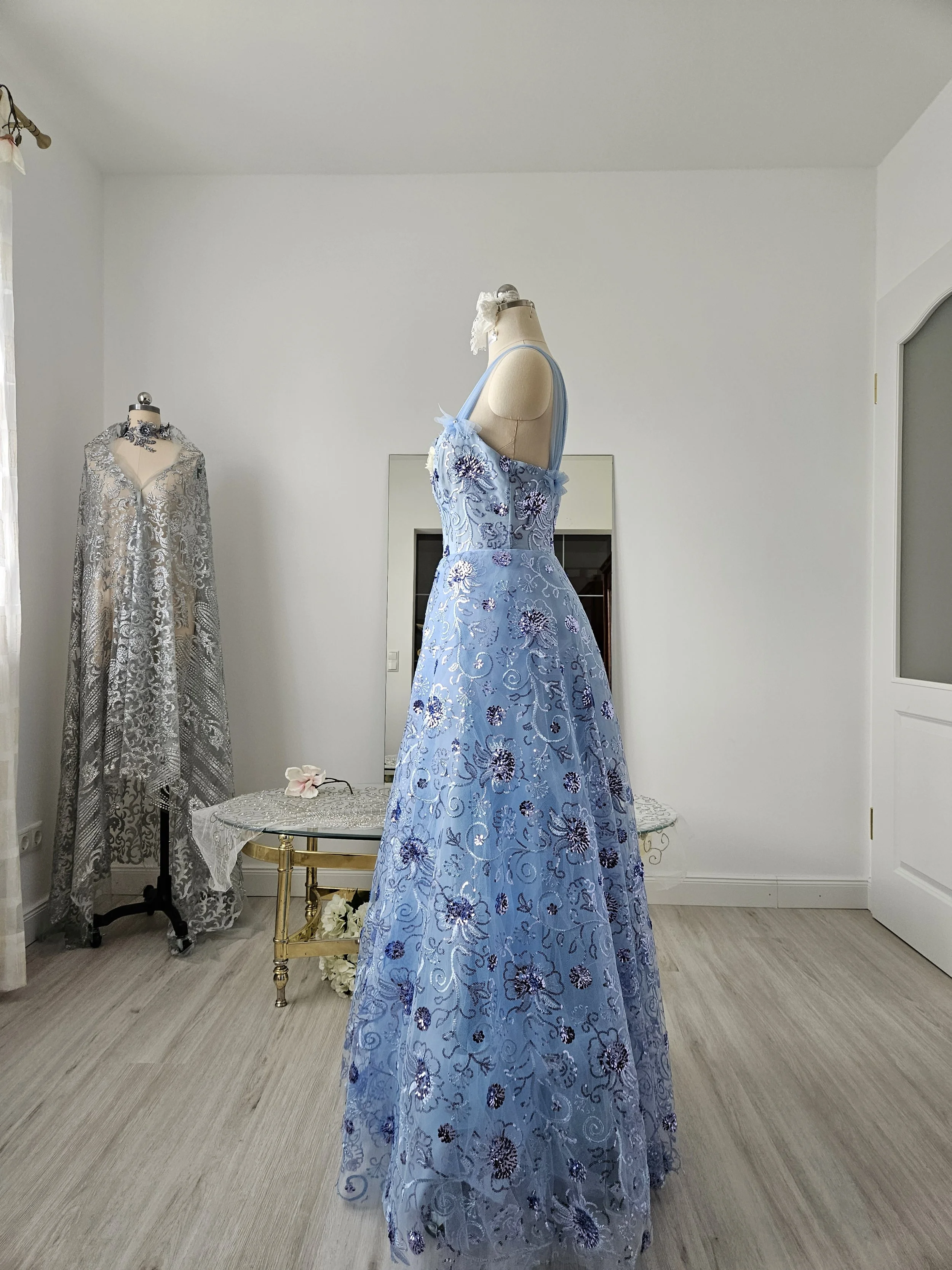 Abendkleid aus eisblauem Tüll mit floralen Glitzerpailletten, Herzausschnitt und breiten Trägern. Es hat eine weiße Zierblüte und Perlen- und Strassornamente . Couture aus Deutschland.