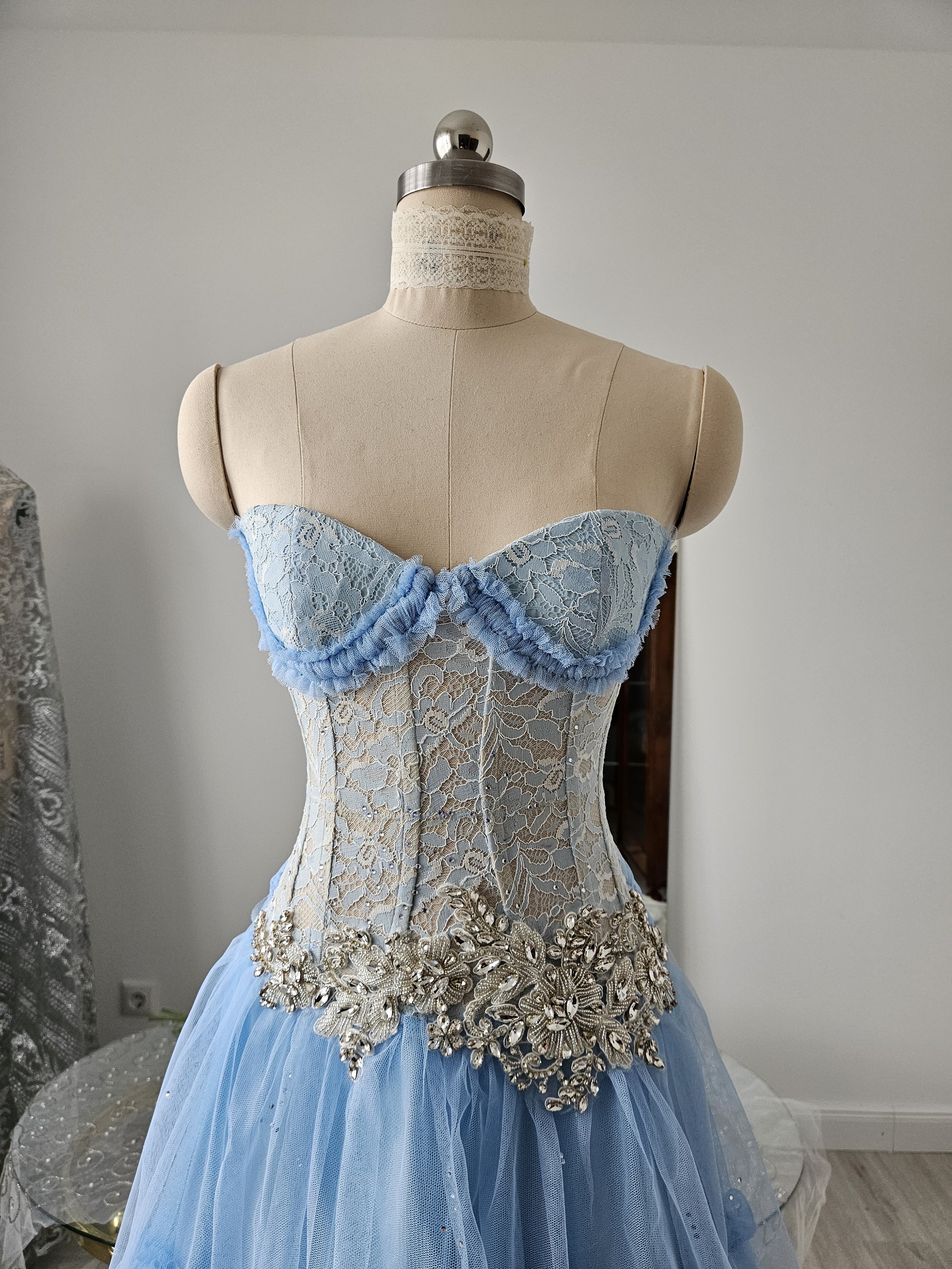 Korsettkleid aus Tüll und Spitze in hellblau / periwinkle, mit hochwertiger, glitzernder Brautkleidapplikation, mit ausladendem, abgestuftem Tüllrock in Bodenlänge. Couture-Kleid für den roten Teppich