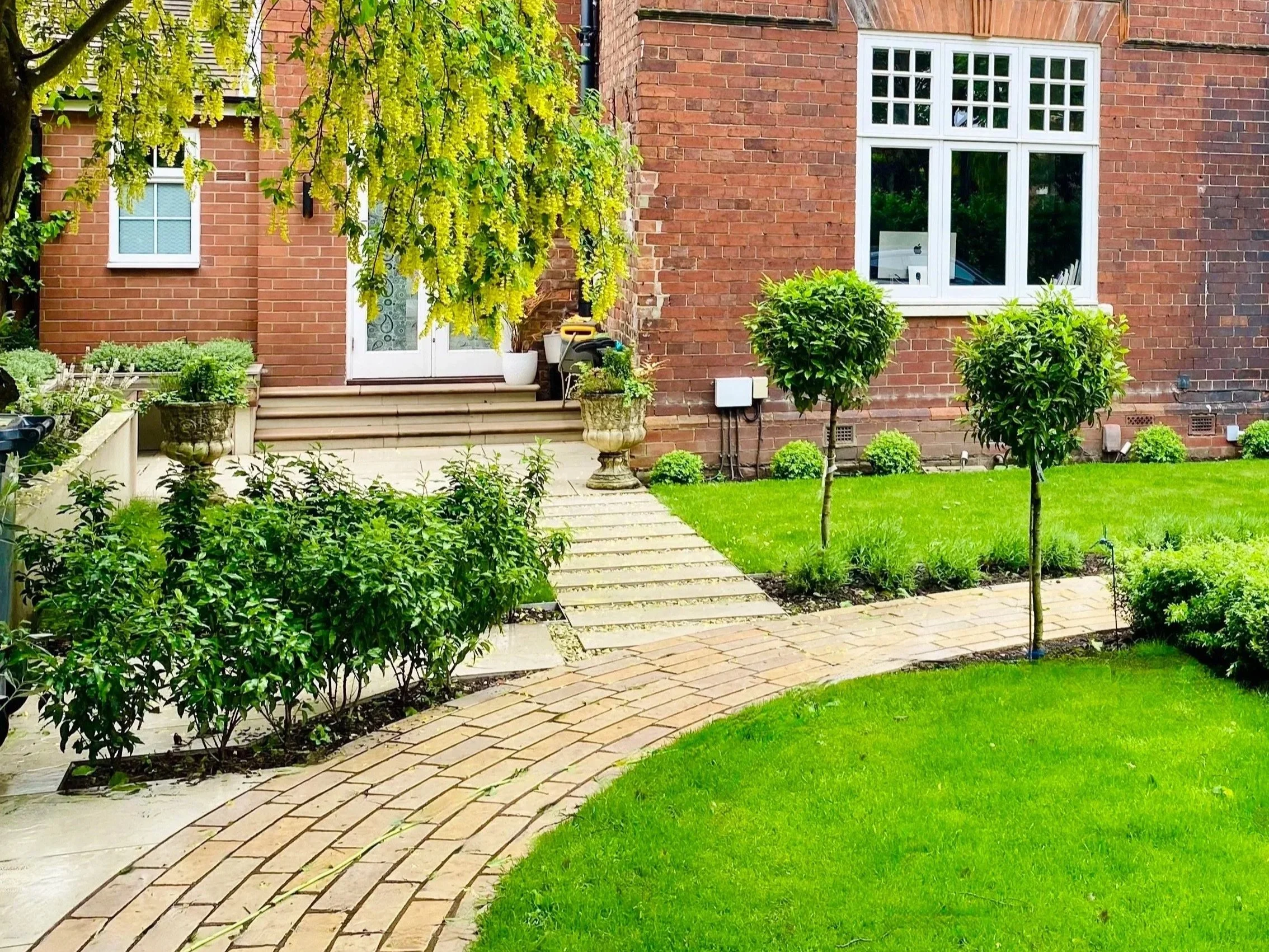 A photograph of the path curving round to the front door, with a secondary stepping stone path leading to the side garden
