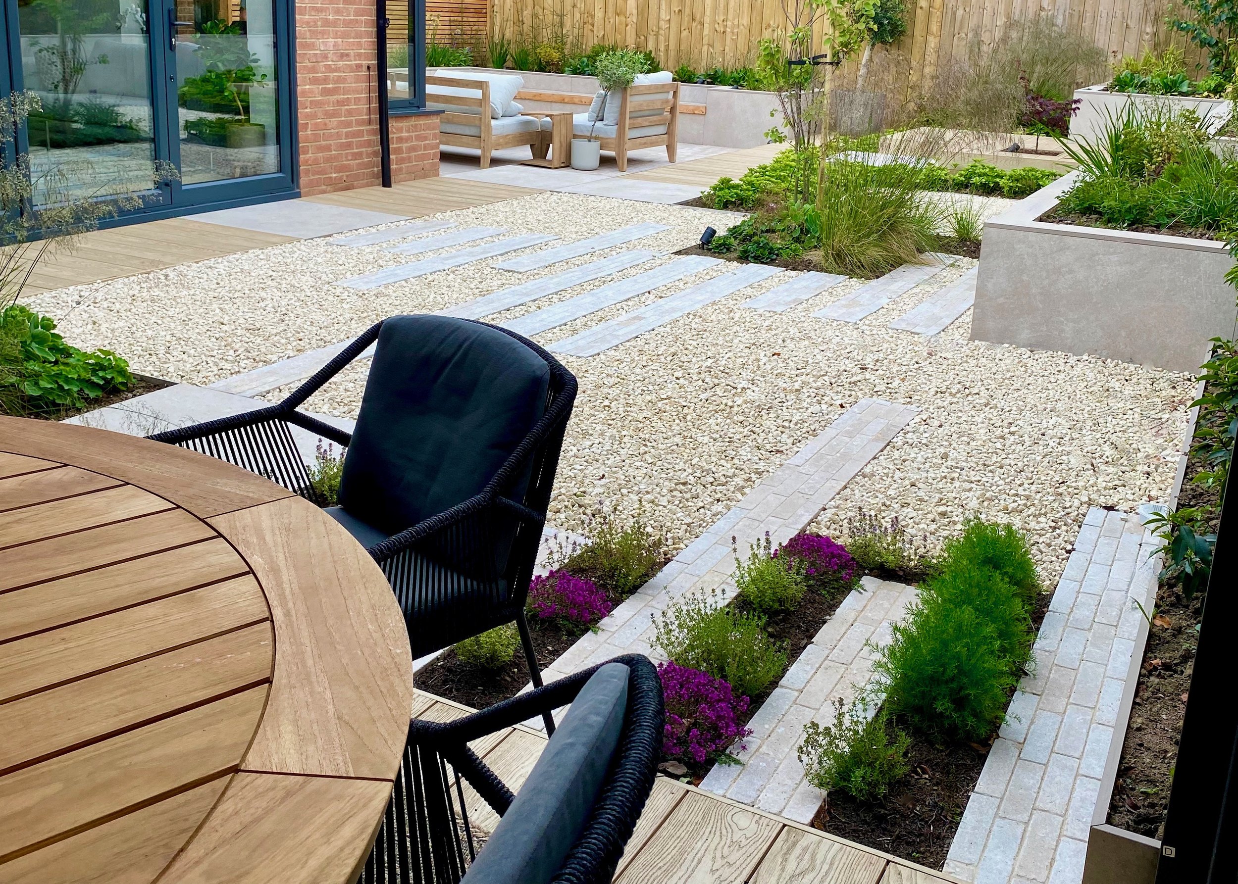 An image showing the view from an outside dining area over a sunny courtyard garden
