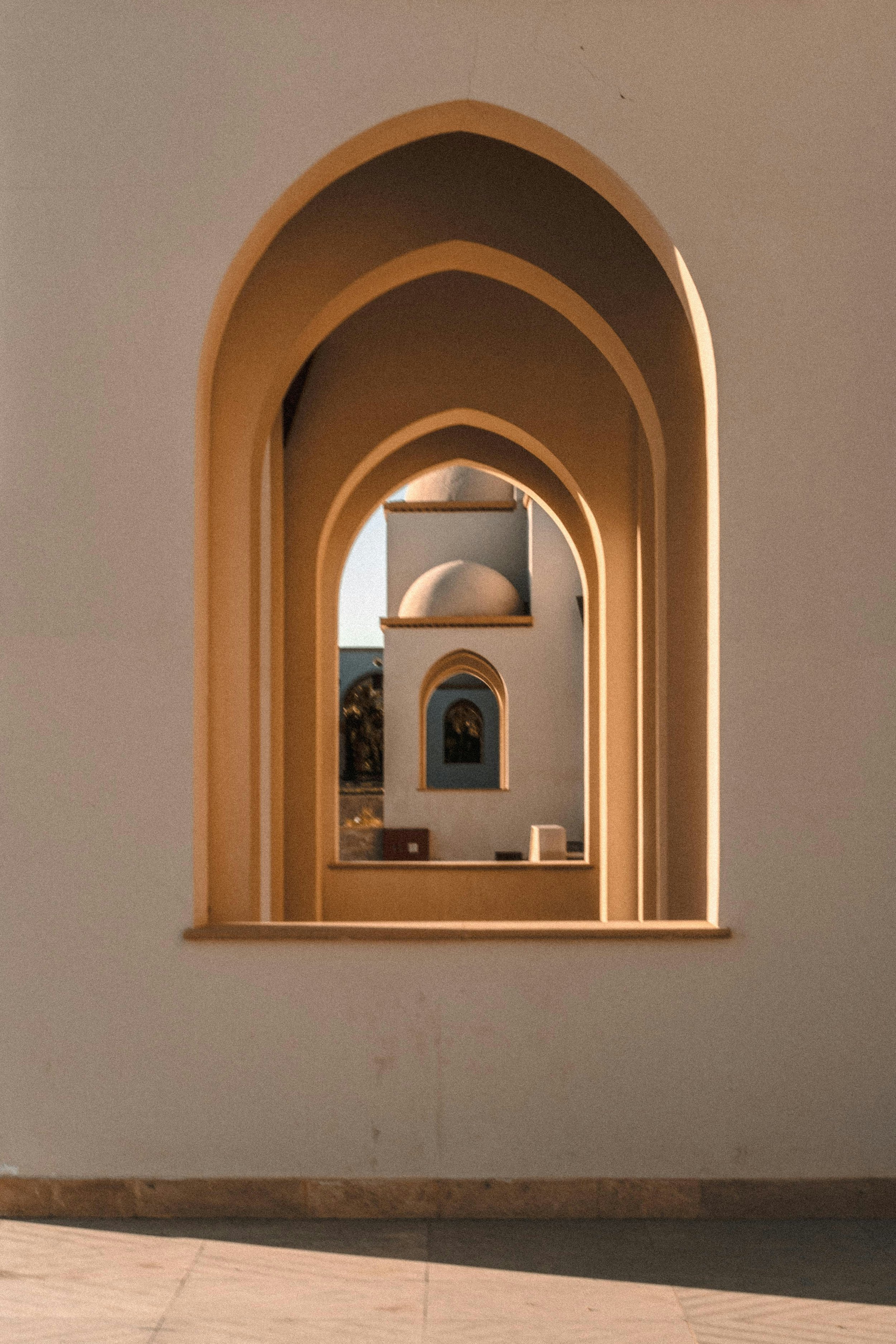 Multiple arched windows or doorways with a building visible through the opening, creating a tunnel-like effect, in warm natural lighting.