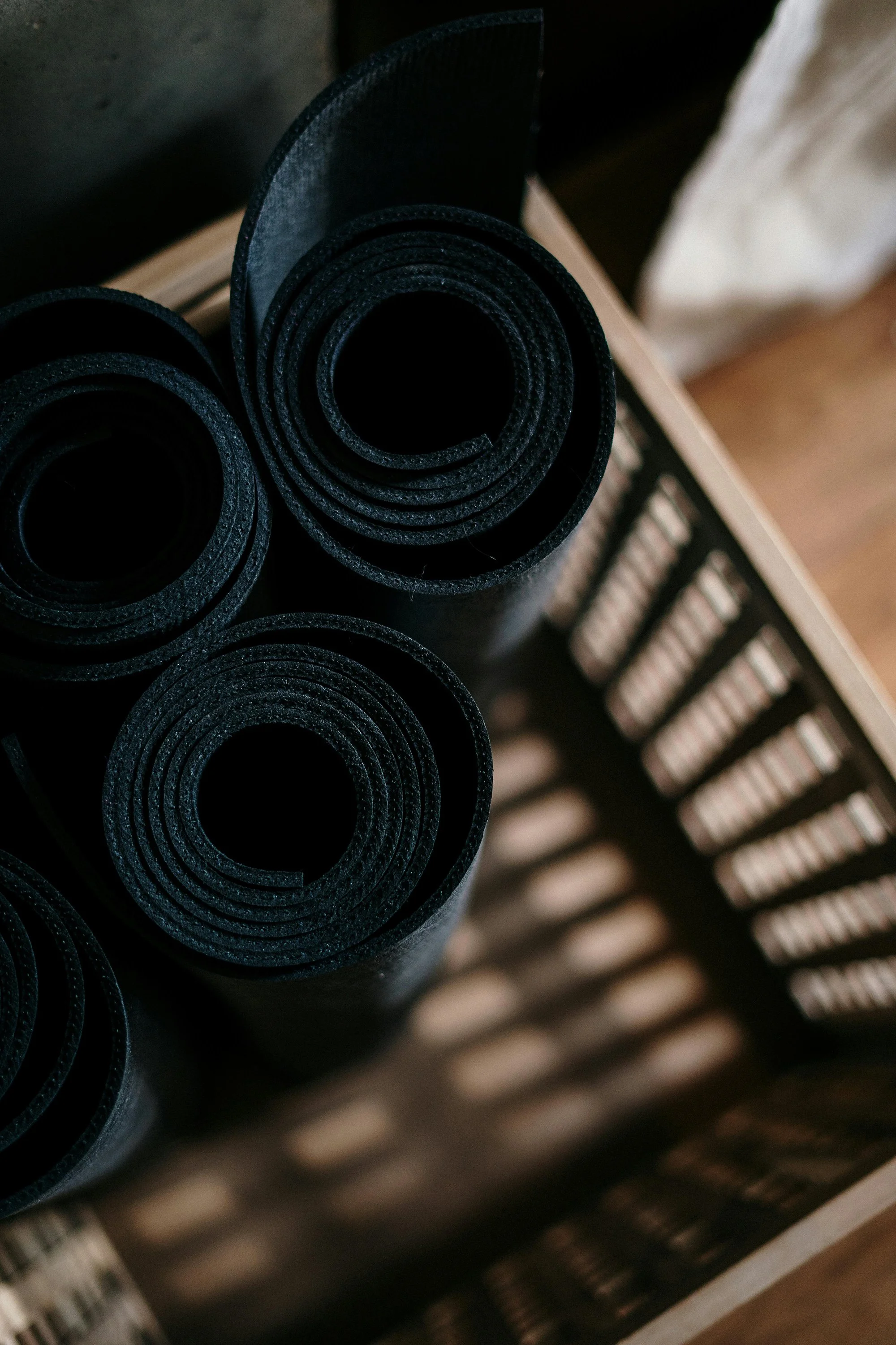 Rolled-up black yoga mats in a wooden basket.