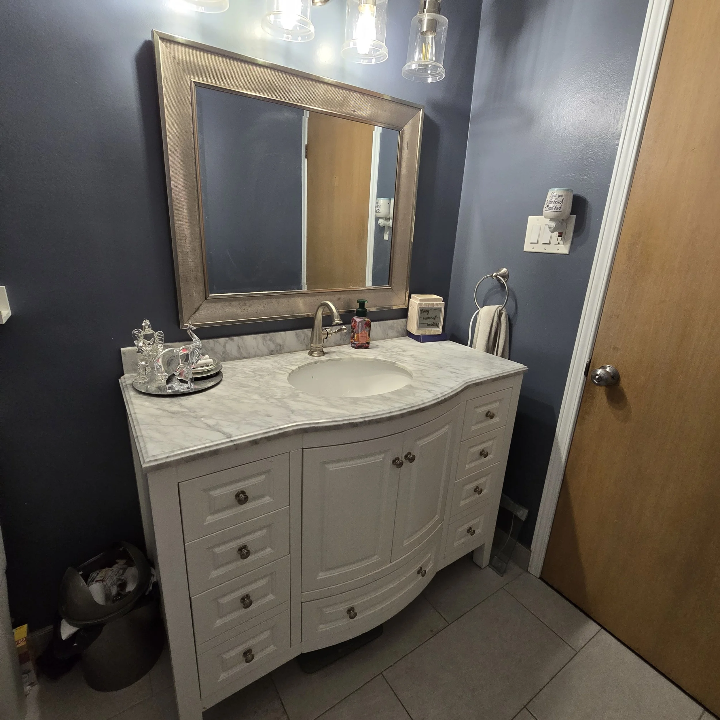 image showing newly installed Victorian style vanity, mirror and lighting, with Yacht Blue paint by Behr and large format floor tile.