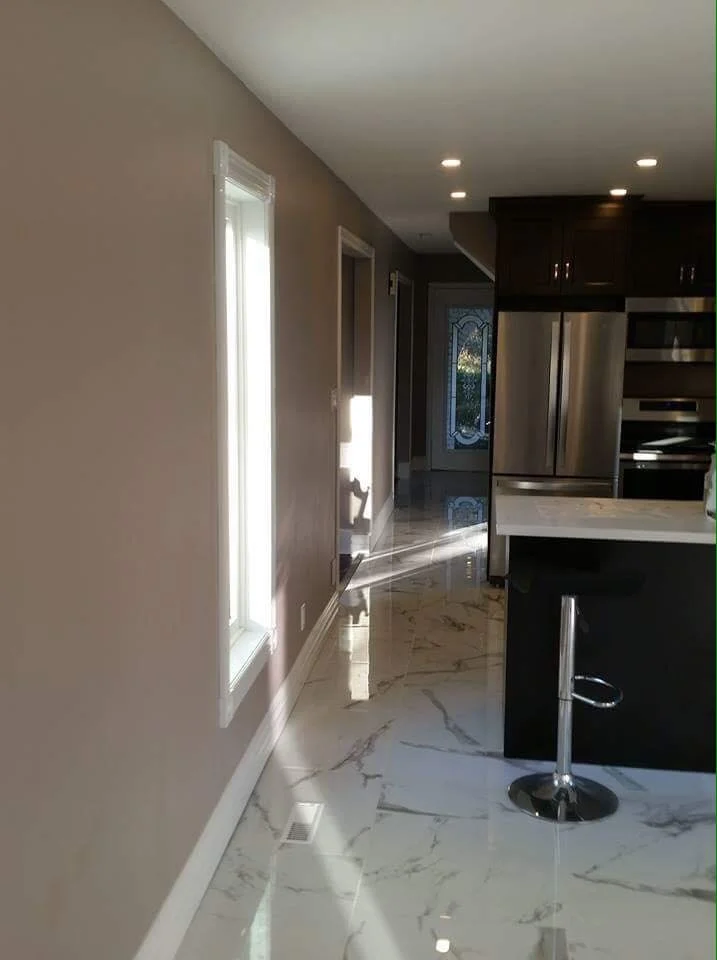 Kitchen with marble tile floors, dark wood cabinets, stainless steel refrigerator, and a white countertop with a bar stool.