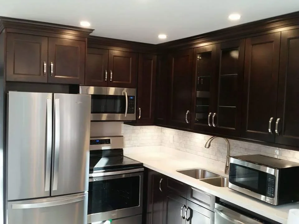 Custom dark maple kitchen renovation in London, Ontario featuring shaker-style cabinetry, quartz countertops, stainless steel appliances, subway tile backsplash, under-cabinet lighting, and large-format Carrara marble-look porcelain flooring.