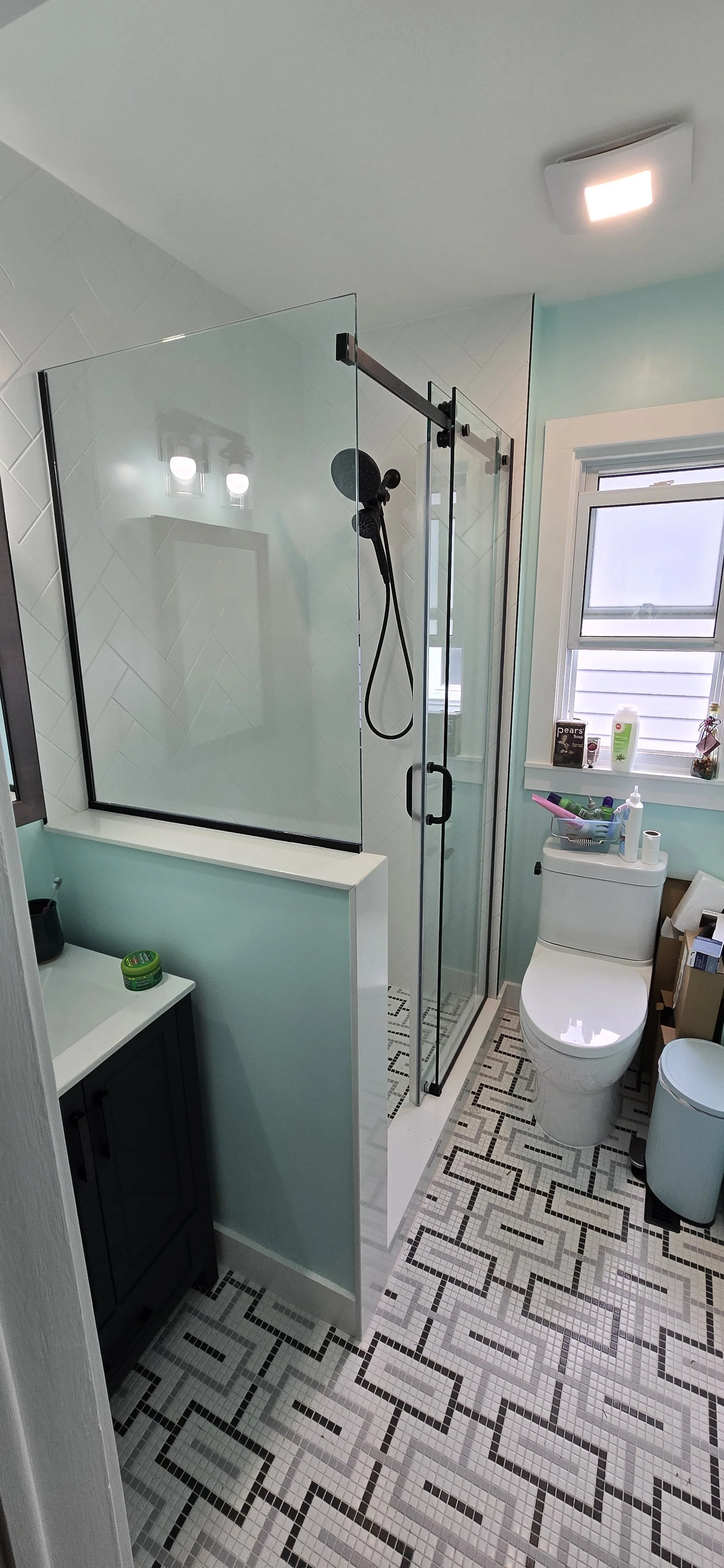 White herringbone shower tile with black trimmed glass enclosure
