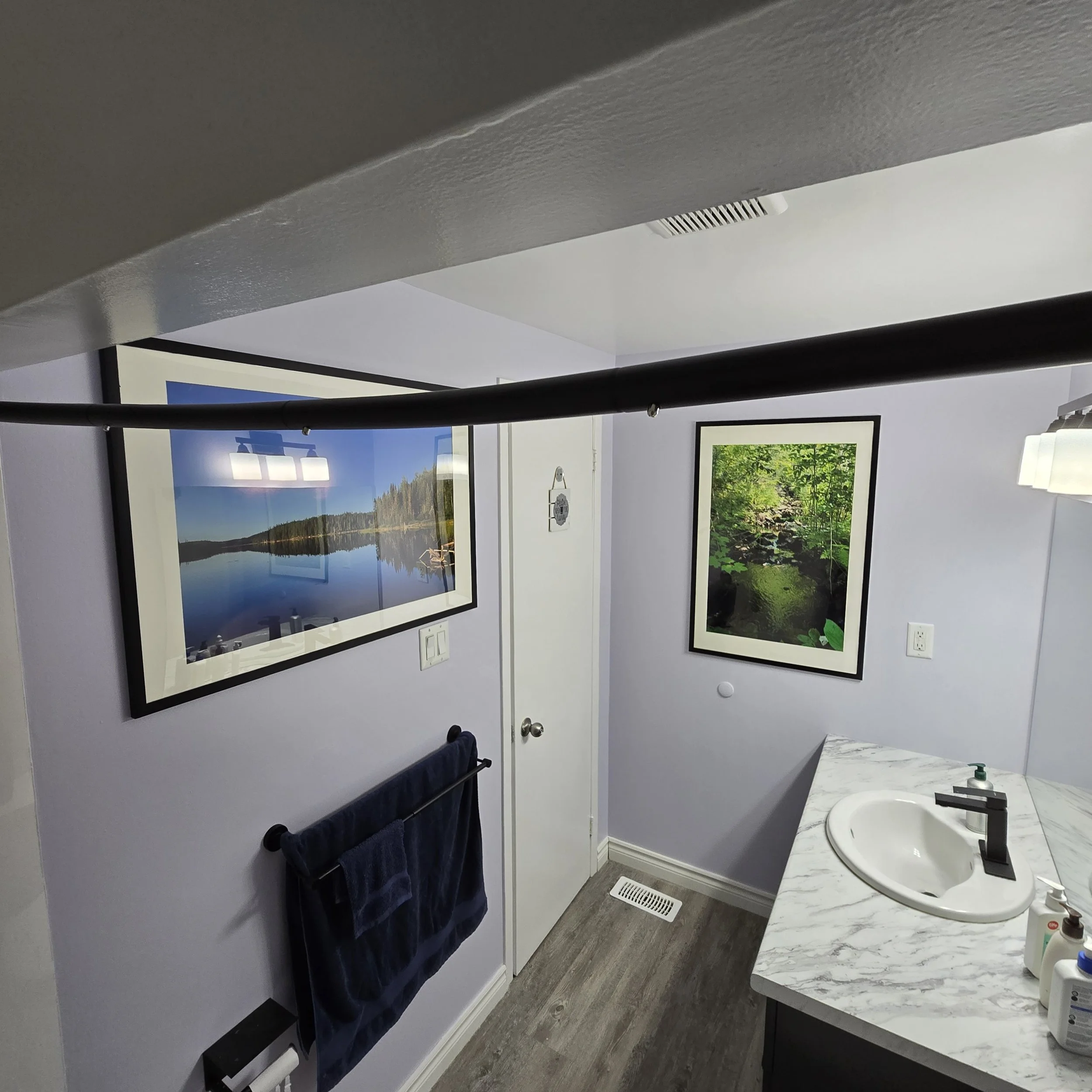 Grey bathroom vanity with quartz countertop, matte black faucet, and modern wall lighting.