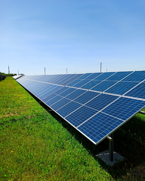 Production d'énergie solaire avec des panneaux photovoltaïques installés dans un champ vert sous un ciel bleu clair.
