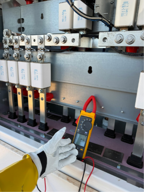 Un technicien effectue une mesure électrique avec un multimètre sur un équipement industriel électrique.