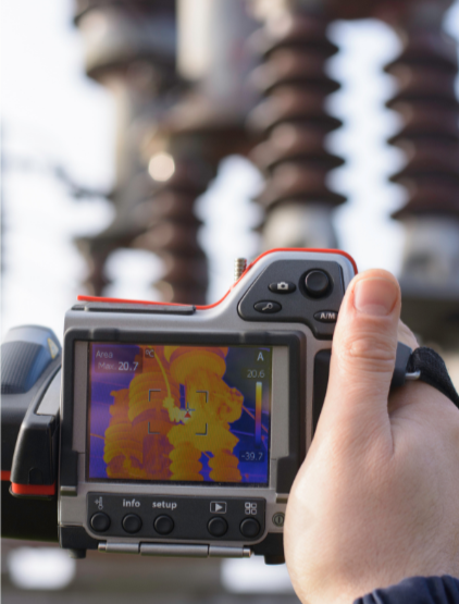 Photographie d'un appareil photo thermique pointé vers un équipement électrique avec des éléments métalliques.