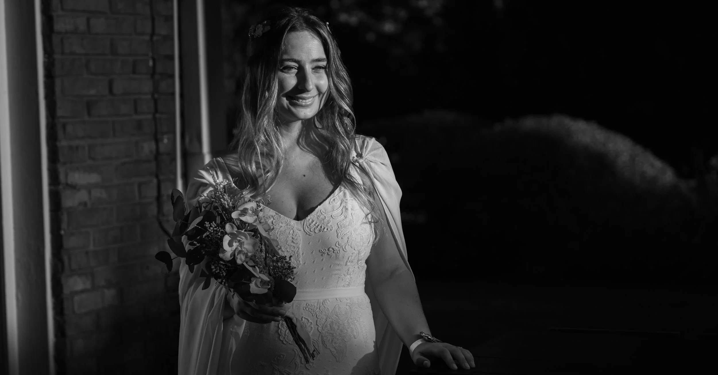 Mujer con vestido de novia sosteniendo un ramo, imagen en blanco y negro.