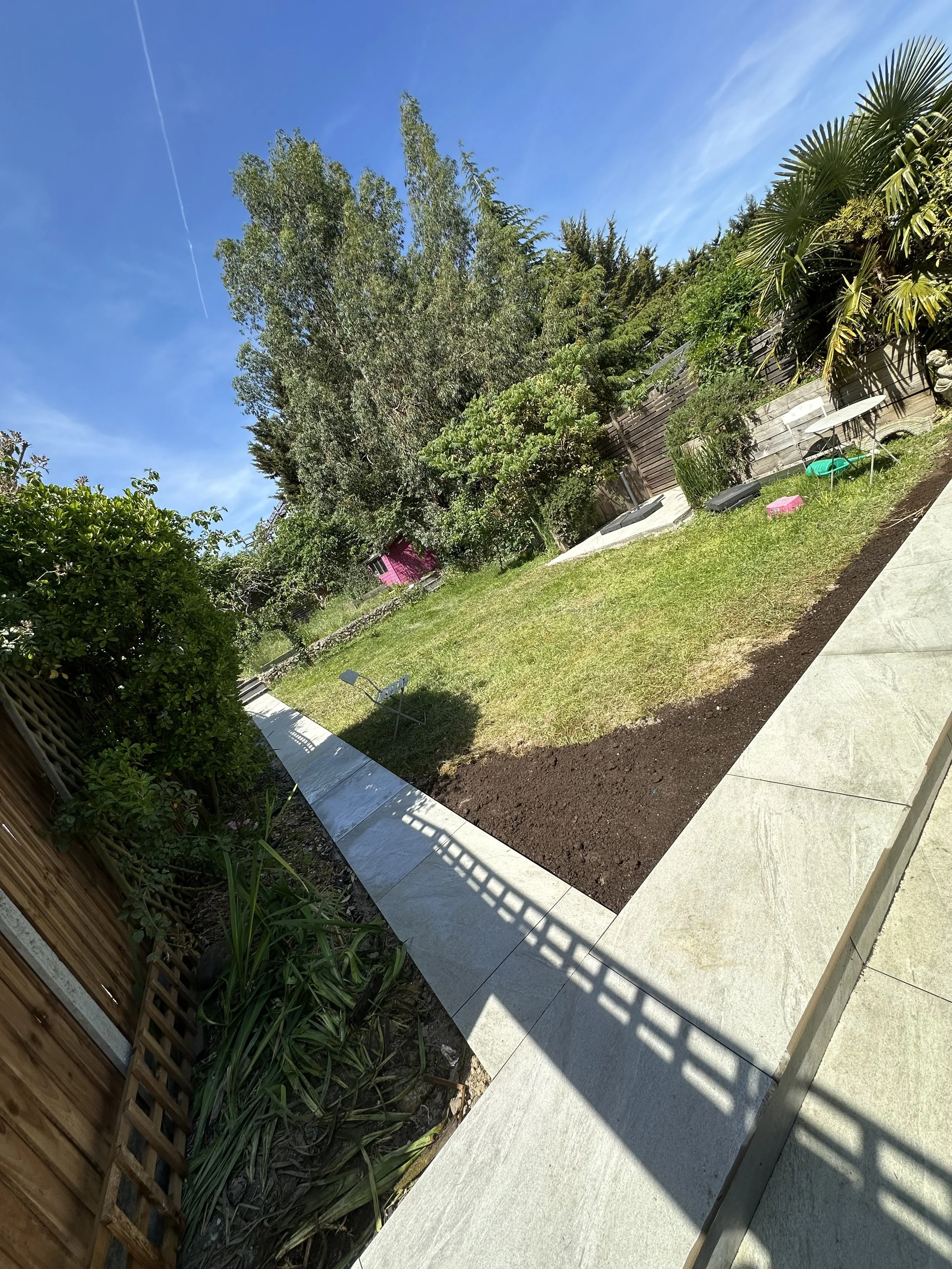 just finished a backyard garden with trees and plants, a wooden fence, a concrete pathway.