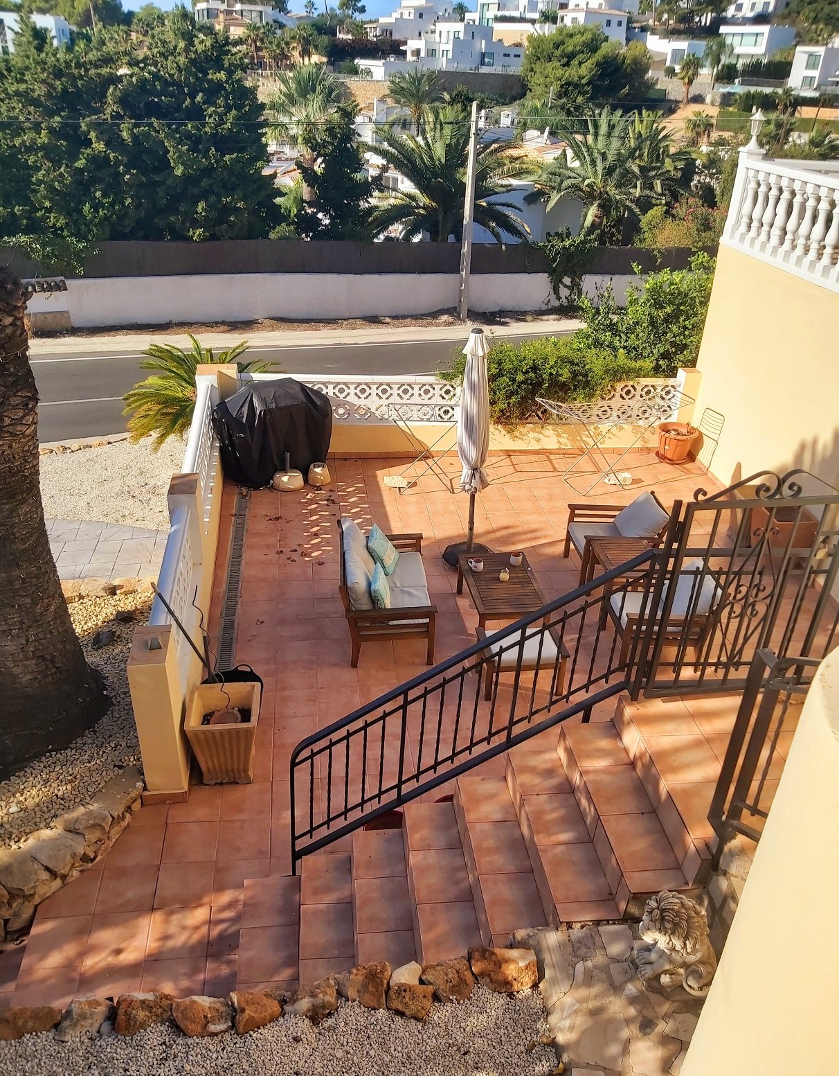 Outdoor patio with terracotta tiles, furniture, stairs, and garden view.