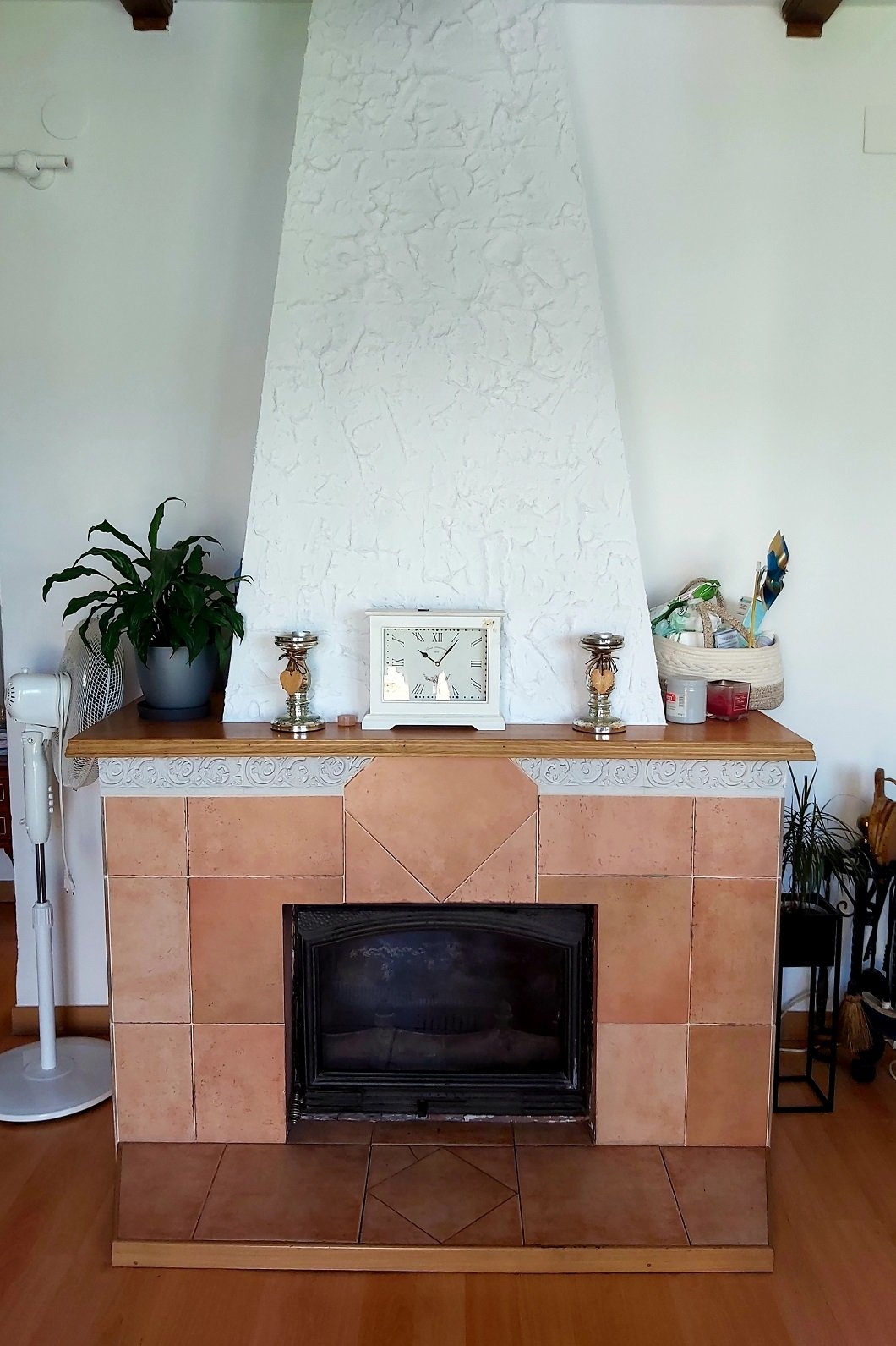 Living room with a tiled fireplace, a plant on the mantel, a clock, and decorative candles.