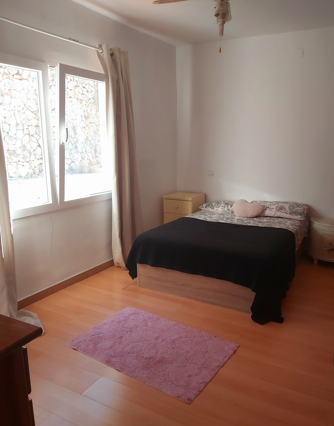 Minimalist bedroom with bed, pink rug, and wooden floor