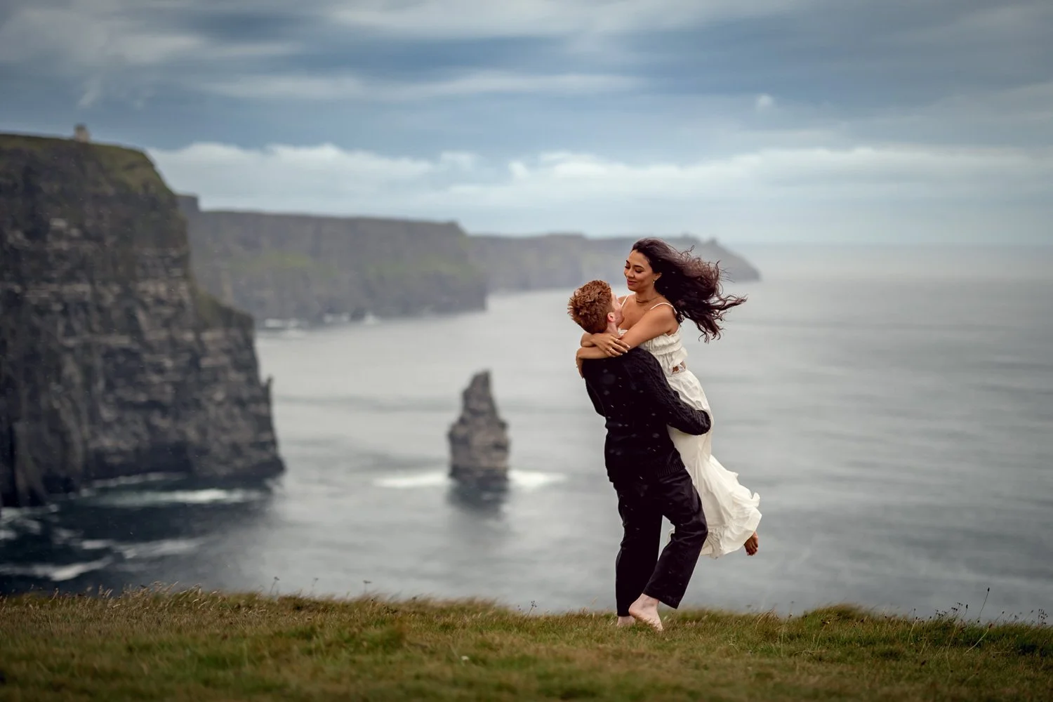 Celebratory moment during an engagement proposal photography session at the Cliffs of Moher as the couple embraces after saying yes.