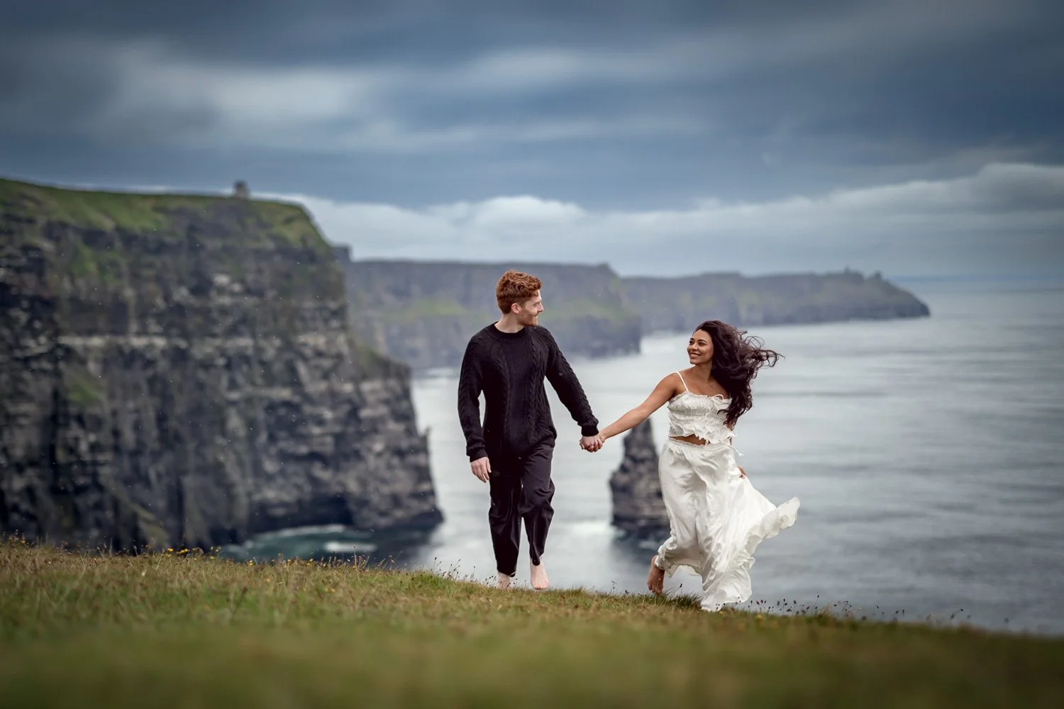 Engagement photography at the Cliffs of Moher showing a couple enjoying the dramatic Irish coastline after their proposal.