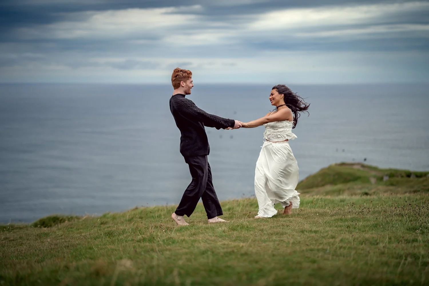 Engaged couple holding hands during an engagement photo session at the Cliffs of Moher in Ireland