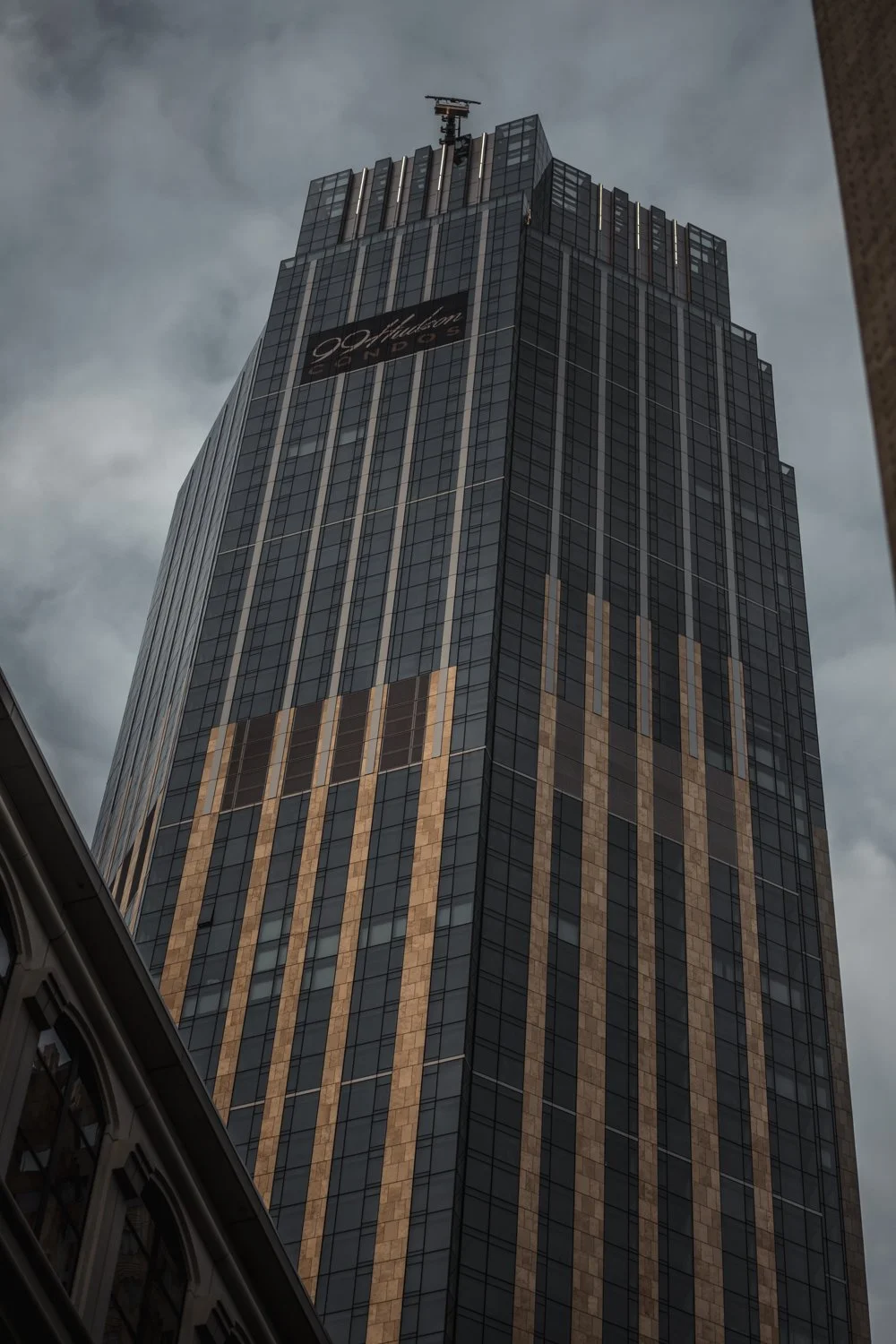 Tall modern skyscraper with a sign for Hilton Hotels and a dark cloudy sky in the background.