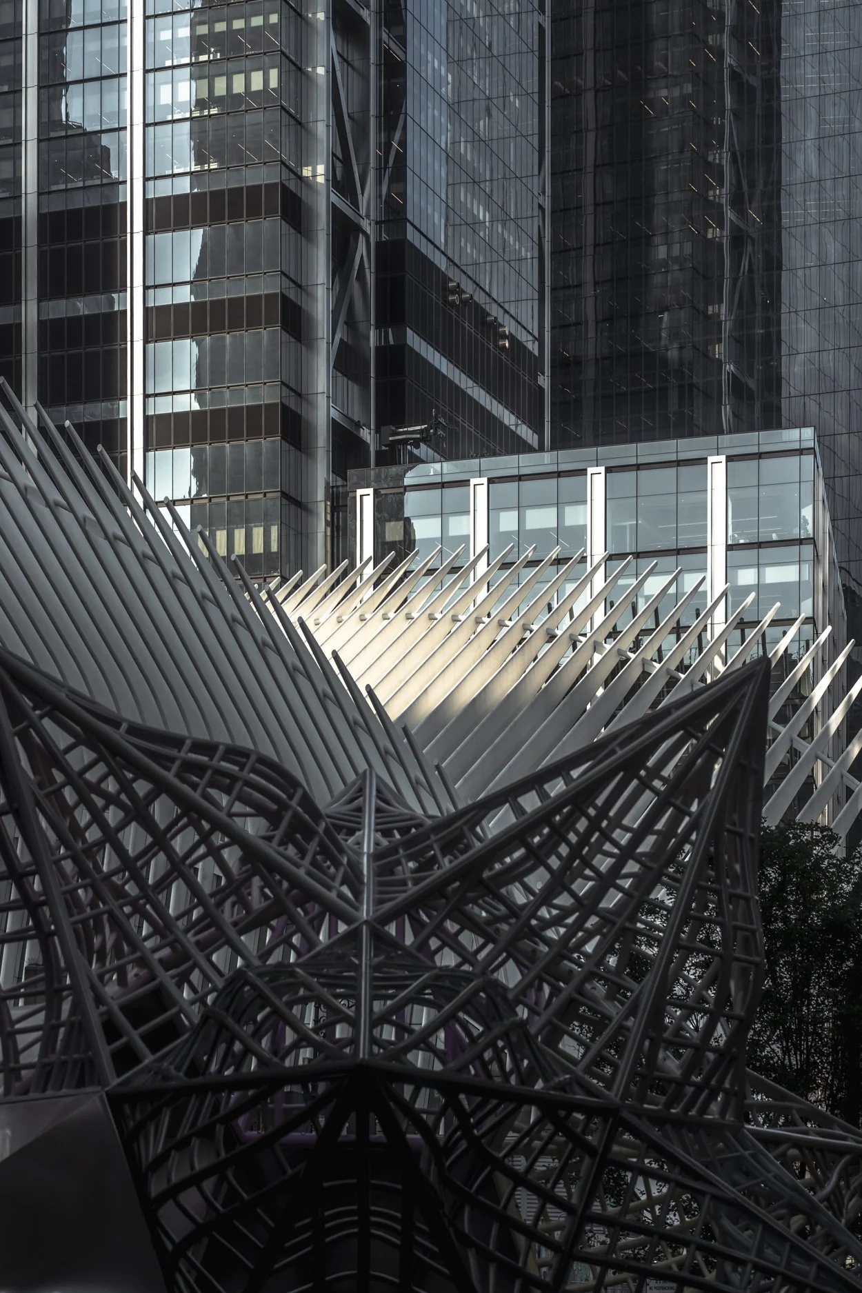Modern skyscrapers with glass facades and an abstract industrial metal sculpture in foreground.