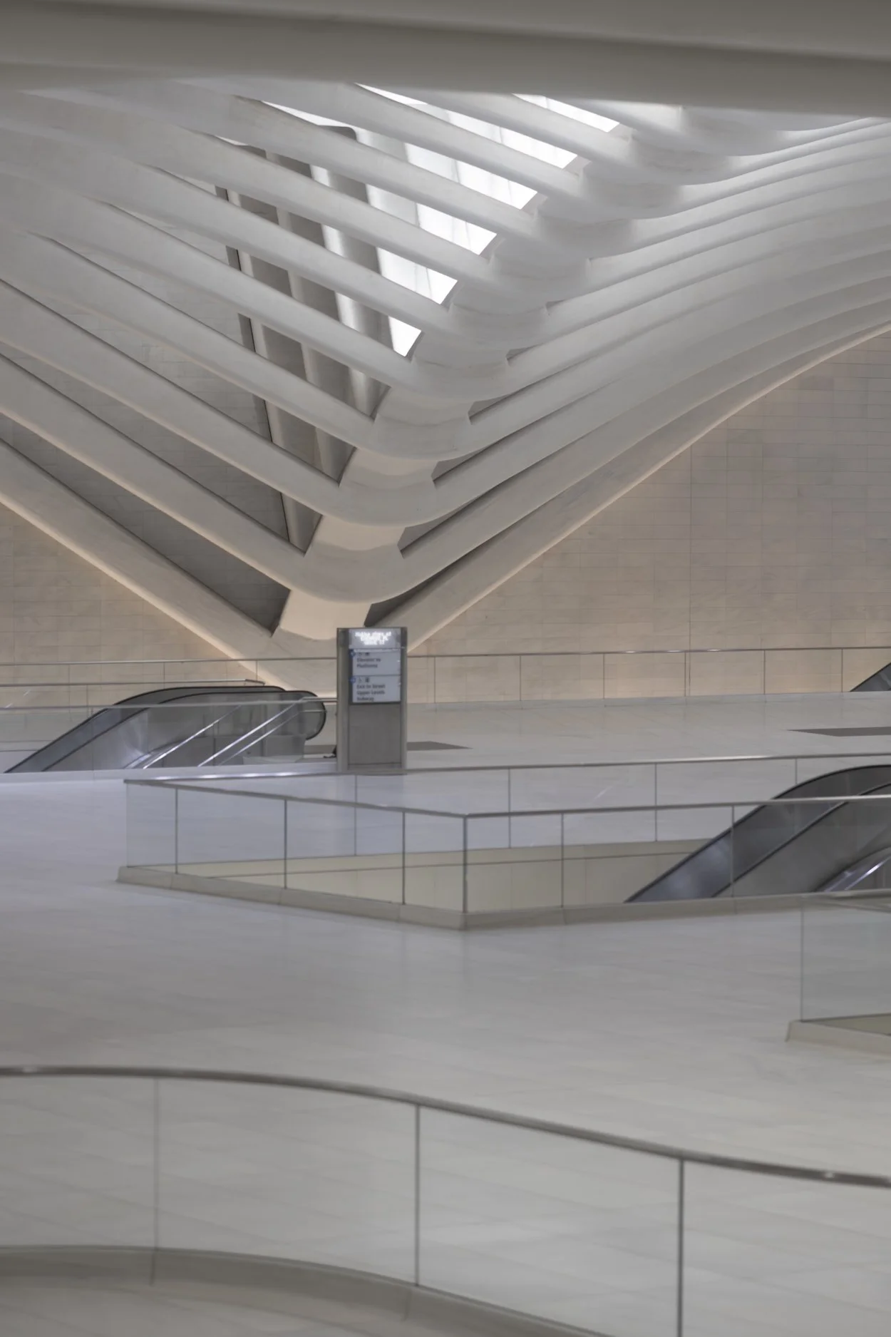 Interior of a modern building with curved white architectural features and escalators.