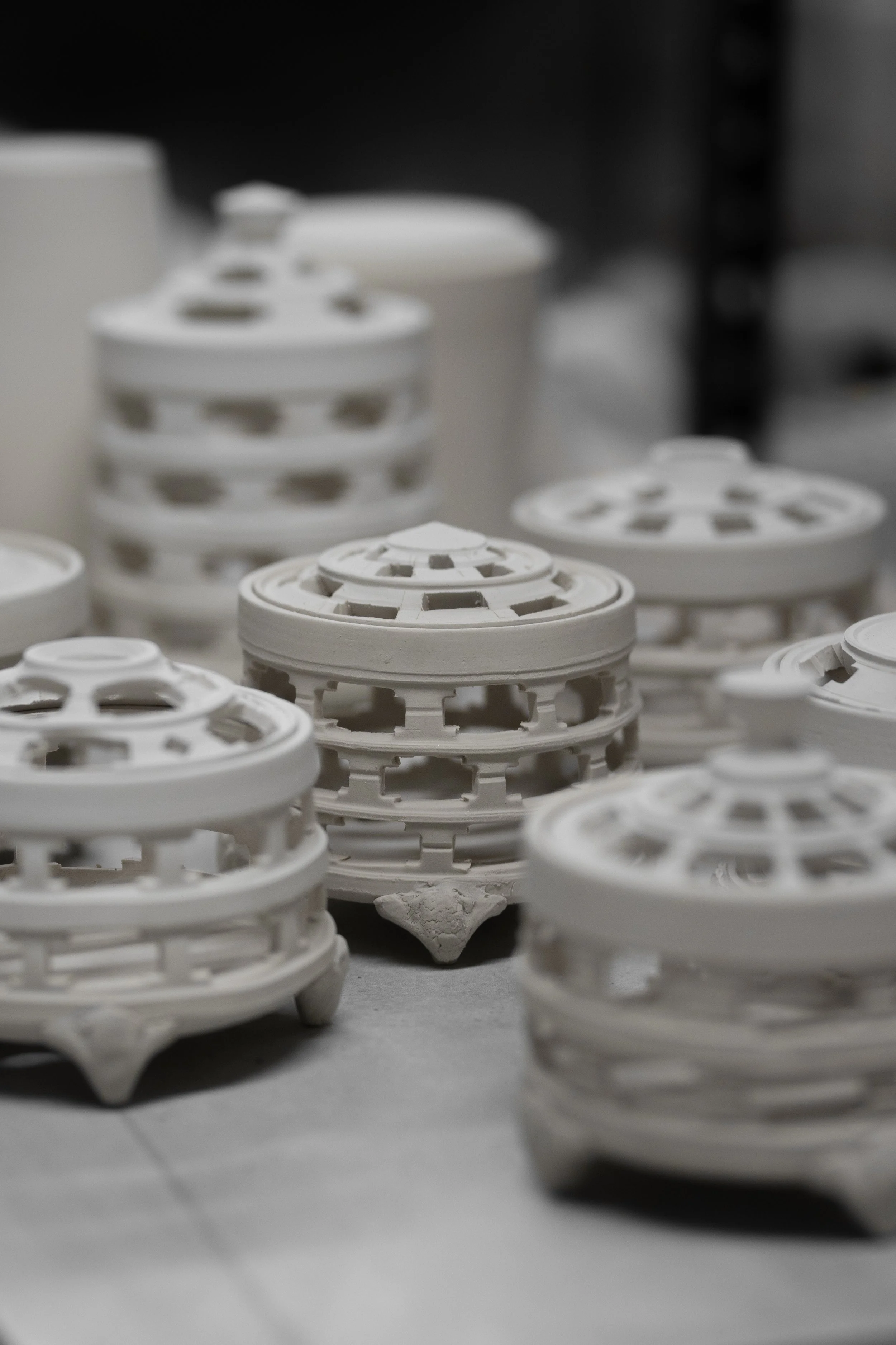 Close-up of multiple white ceramic or porcelain decorative objects with open lattice design, stacked and arranged on a surface.