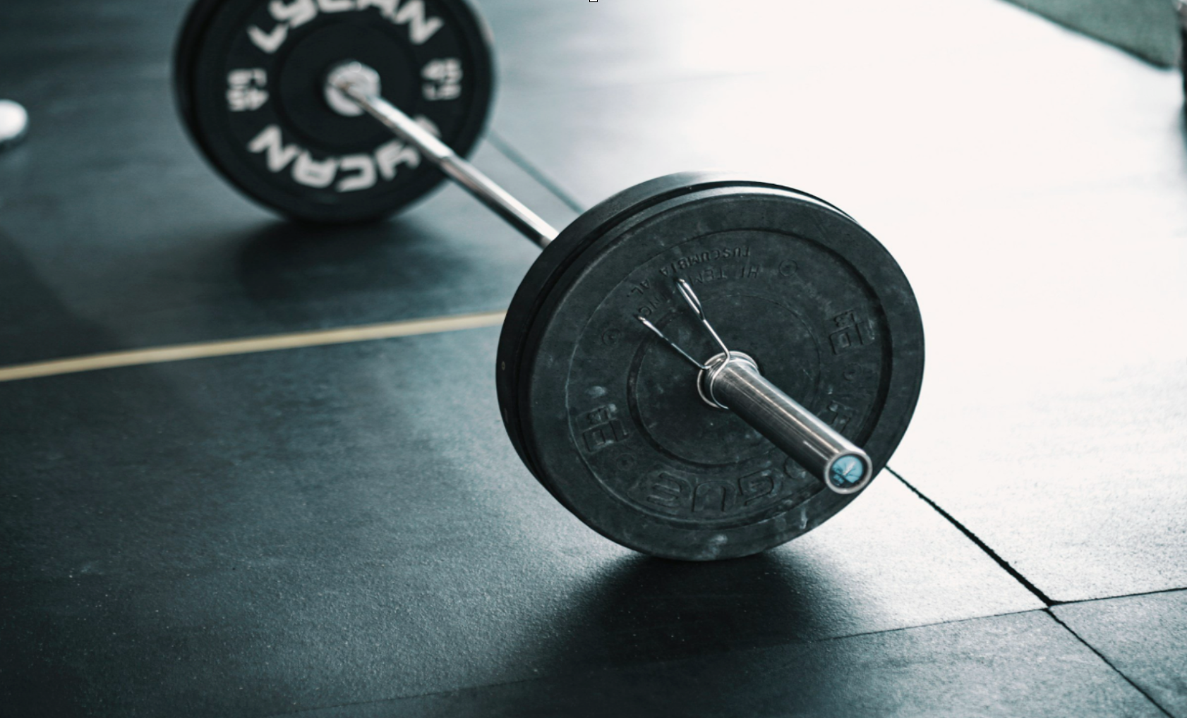 Barbell with weights on gym floor, ready for lifting