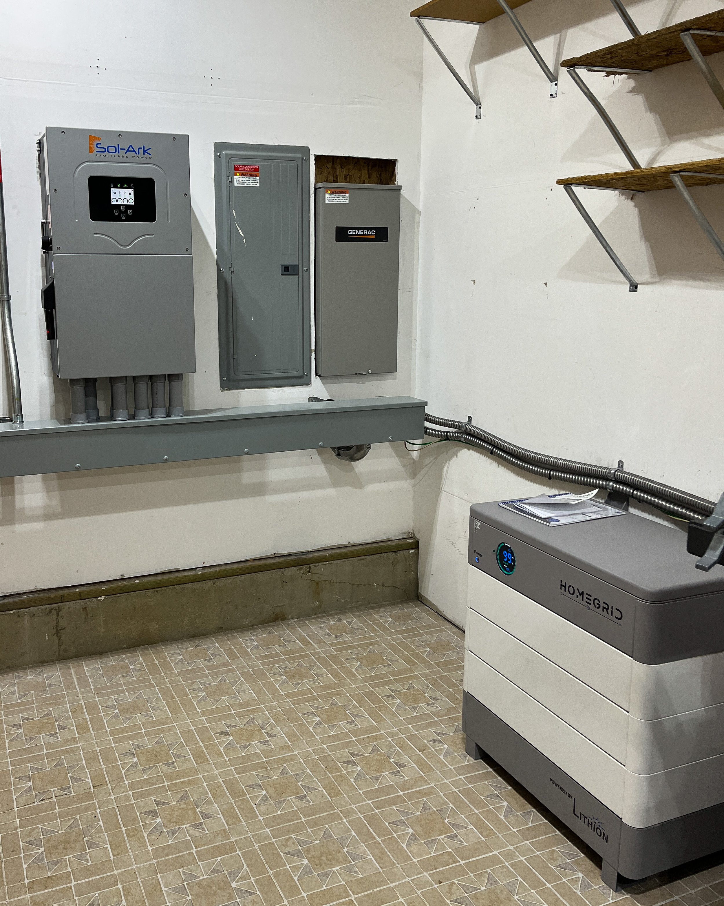 Poulsbo Washington garage with electrical equipment, including a Sol-Ark inverter, a Generac electrical panel, and a HomeGrid lithium-ion battery unit.