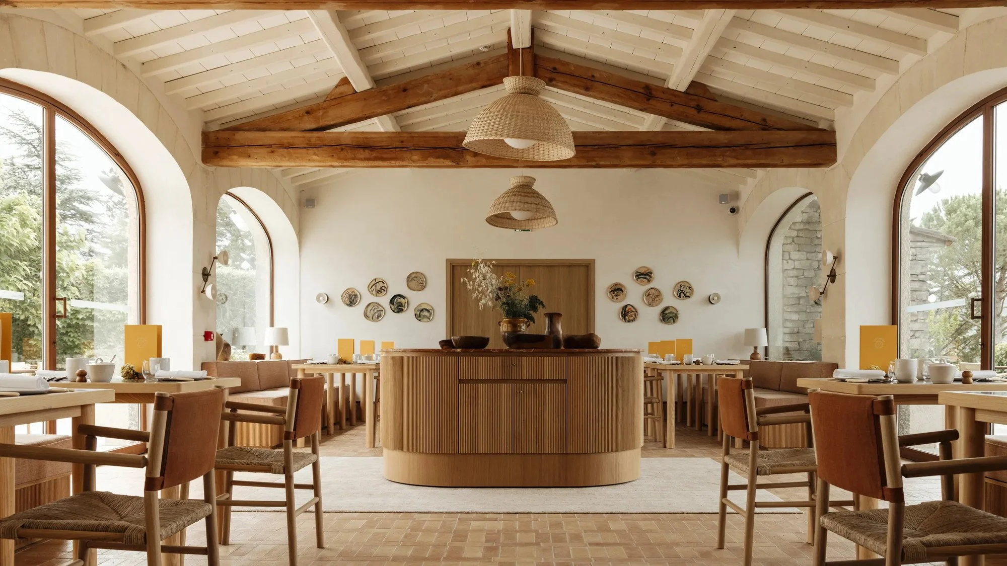 Restaurant dining room at Capelongue with beamed ceiling, arched windows and pale oak furniture, Bonnieux.
